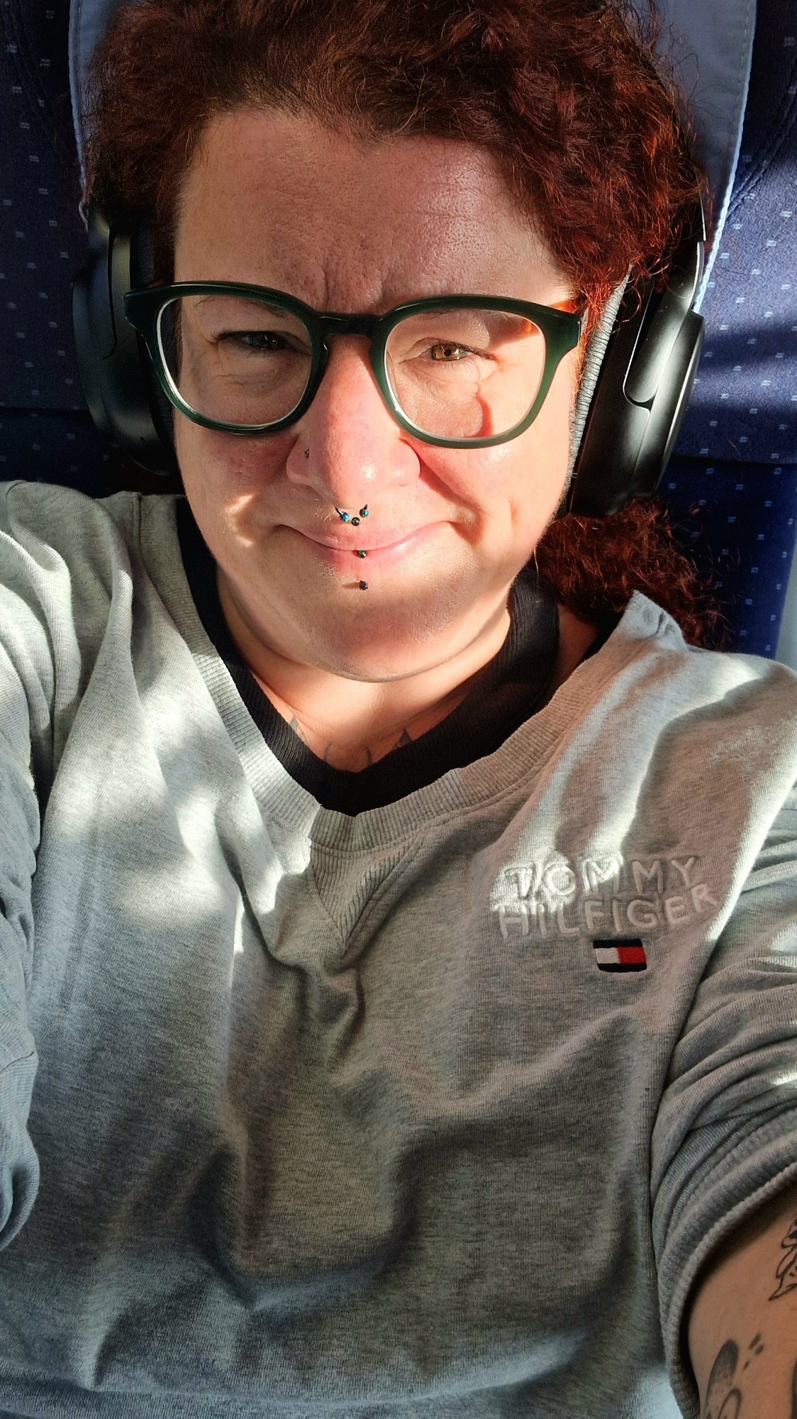 Selfie aus dem Zug.  Sonnengeblendet. Stehen etwas zusammengekniffen. OverEars