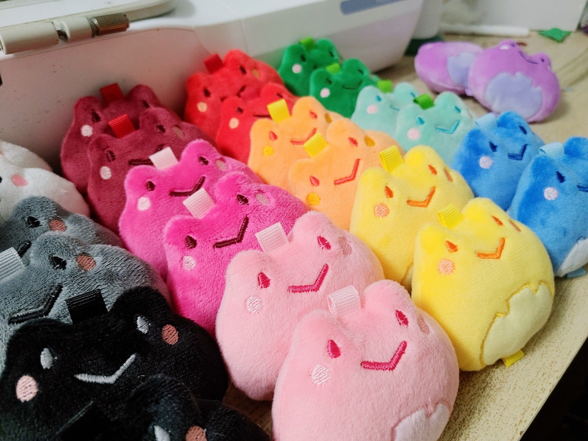 Many small frog plushies in rainbow colors