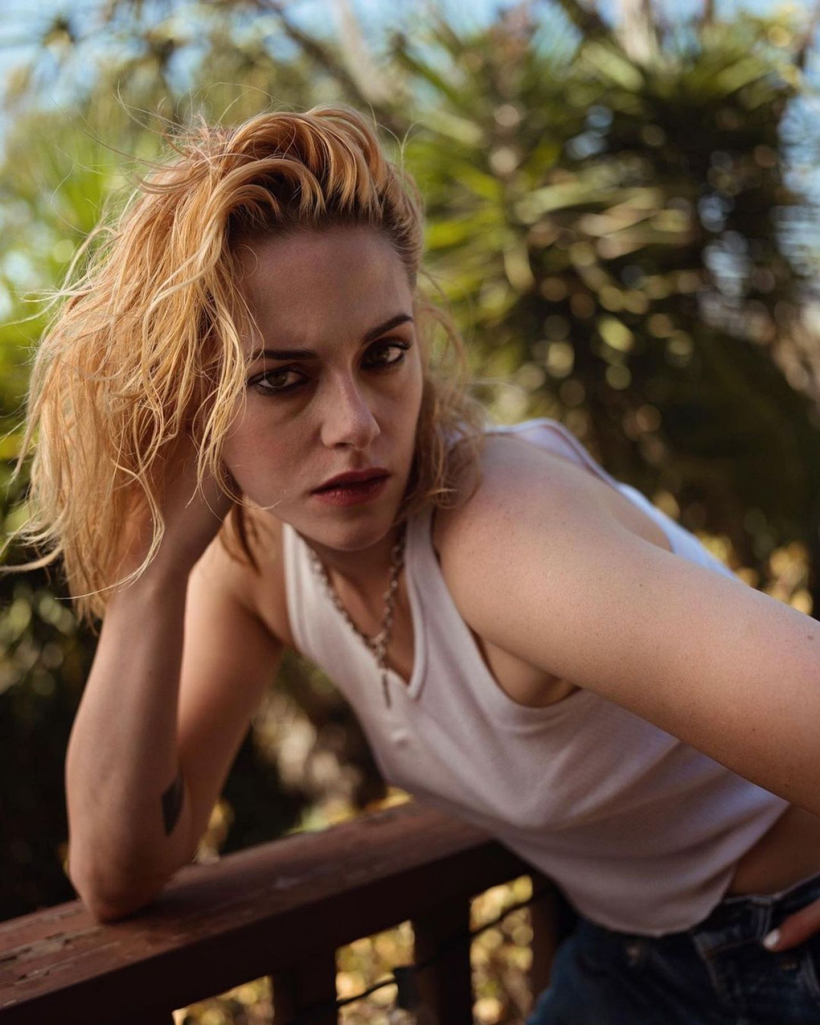 kstew with similar hair to the last pic but side combed and just wearing a white tank top and jeans, leaning into camera, deep eye bags but hot