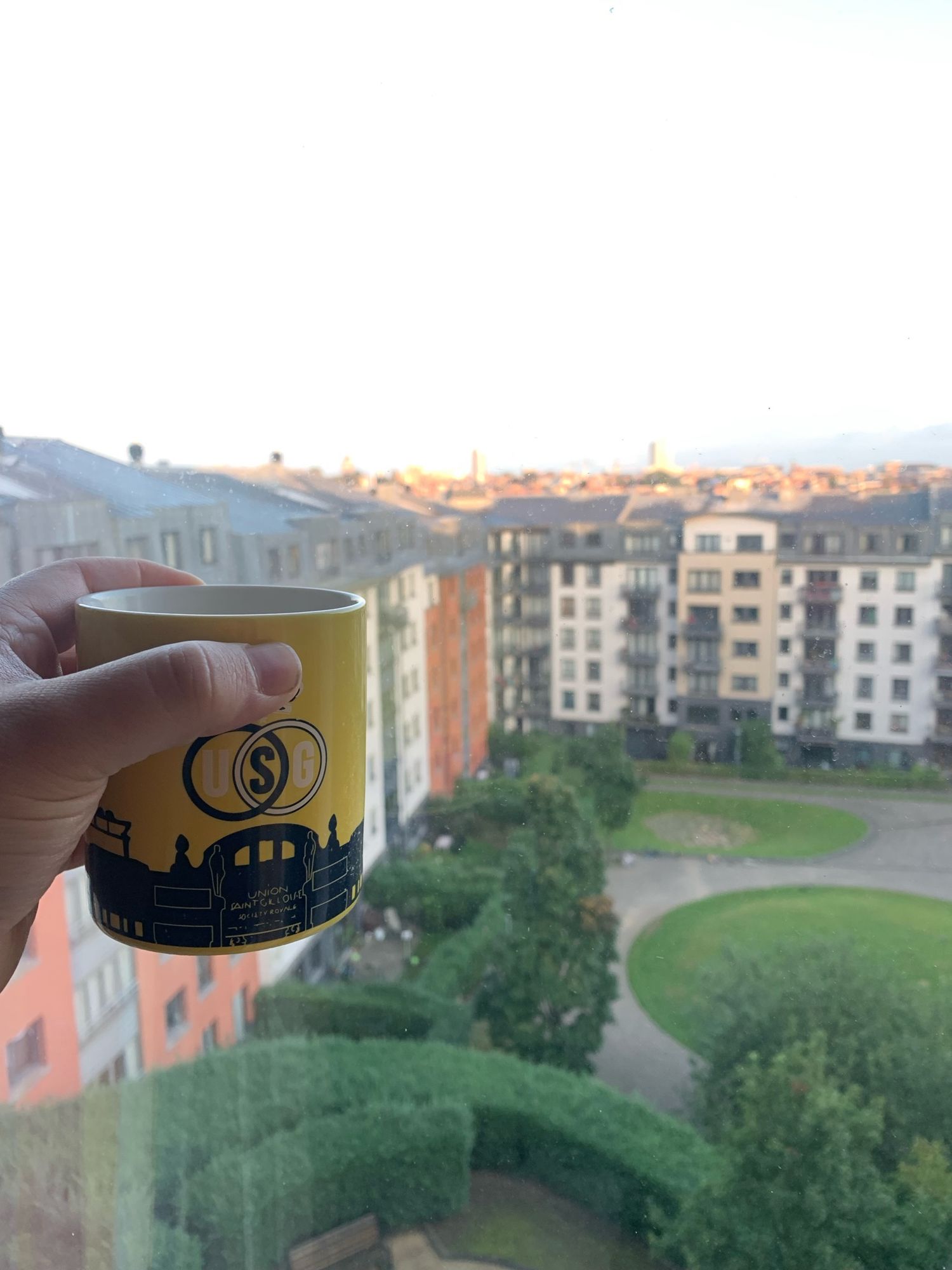 Brüksel'deki son kahve. Yellow coffee mog over an inner courtyard with brussel‘s skyline in the background.