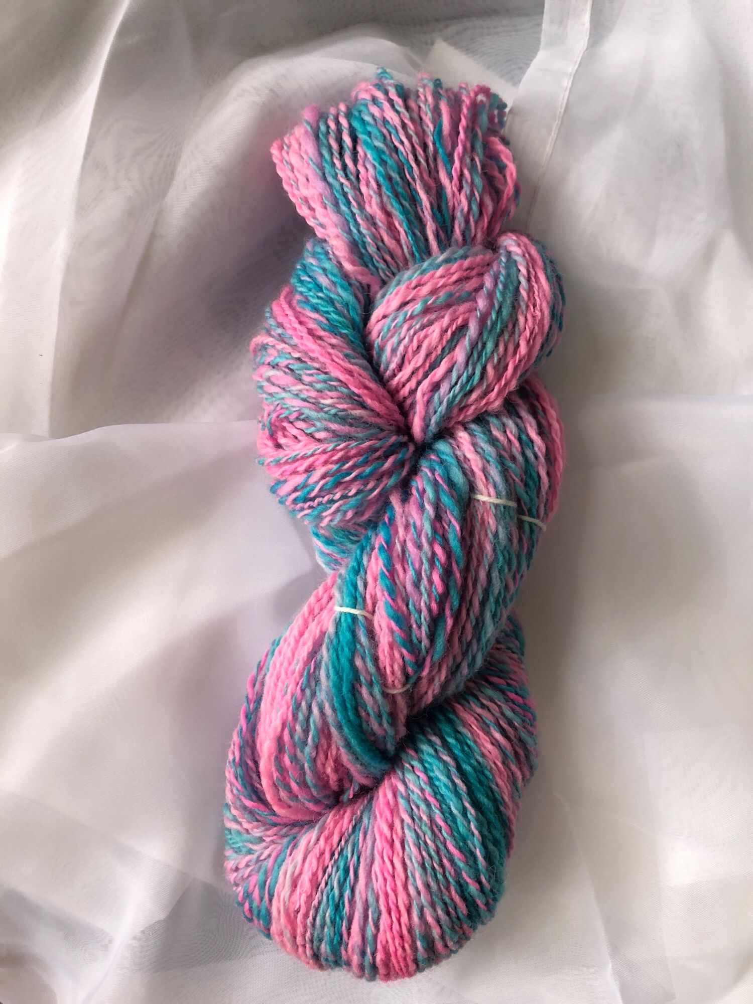 The yarn is plied and twisted into a hank. Now the colors blend and twist into stripes of blue and pink and barberpole combinations of the two spun together 