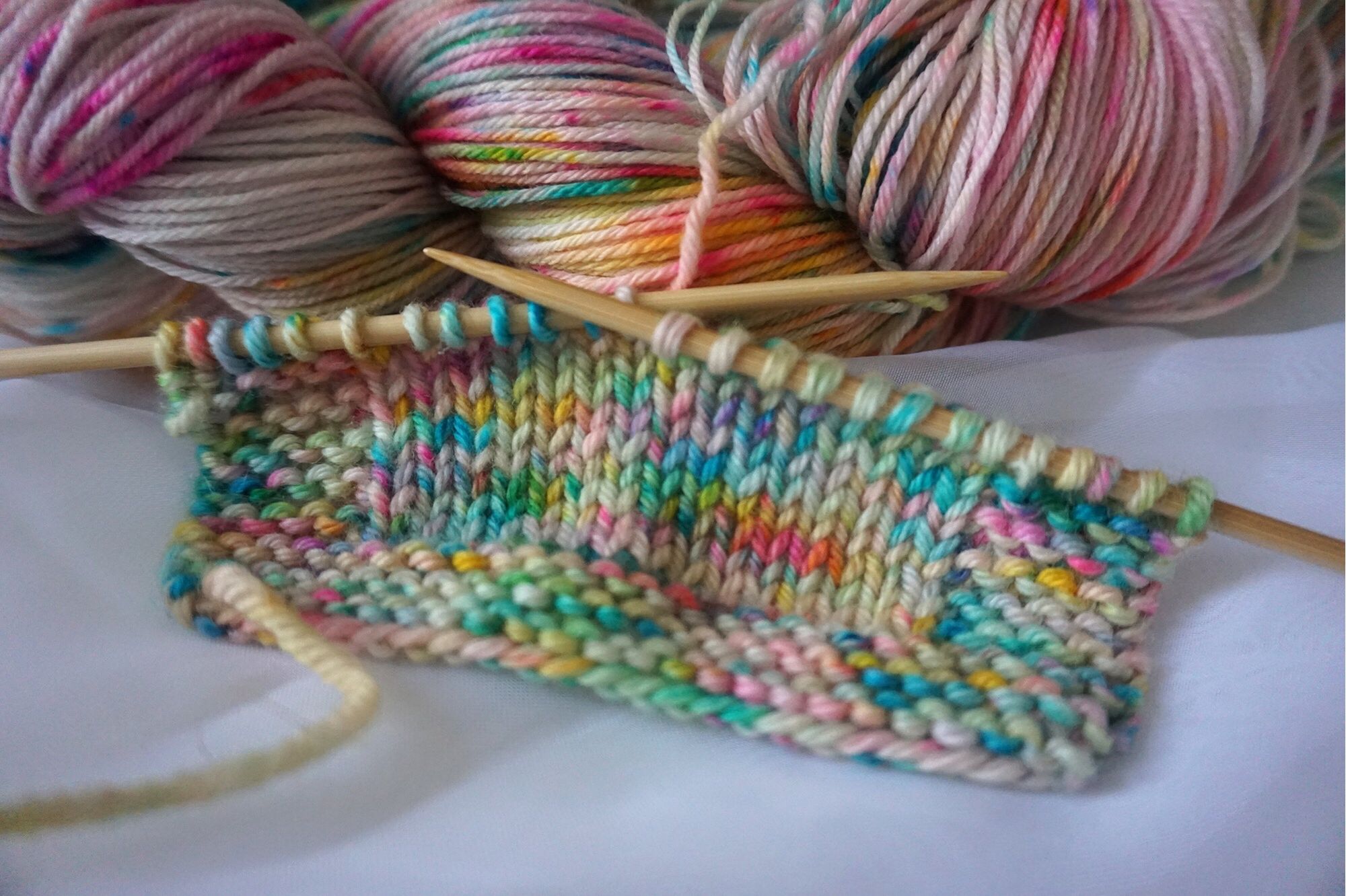 The same yarn knit on a sample swatch. The colors pool and pattern in speckles of colors.