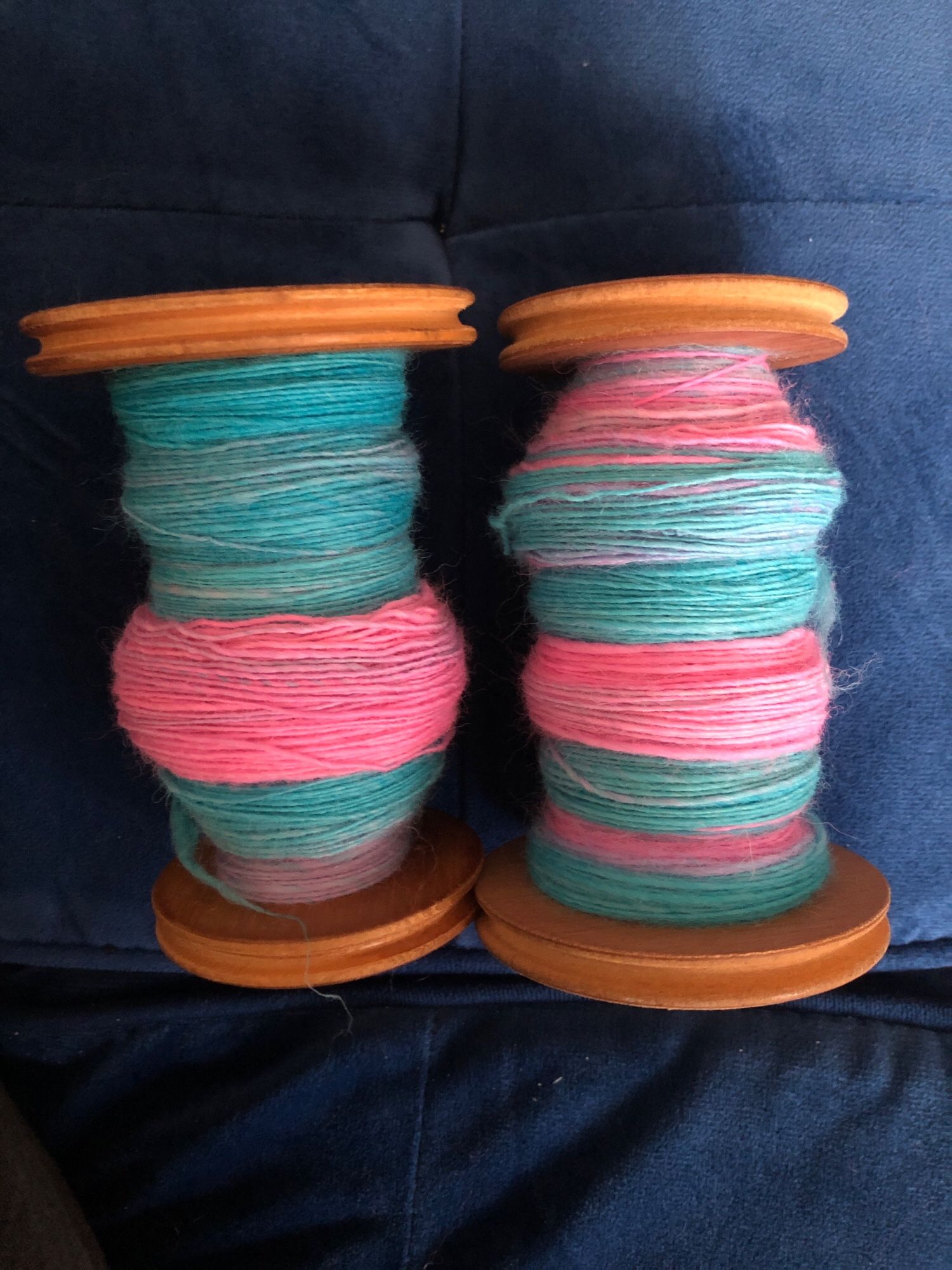 Now yarn has been spun into singles on two bobbins. The yarn stripes in pink and blue like the roving 