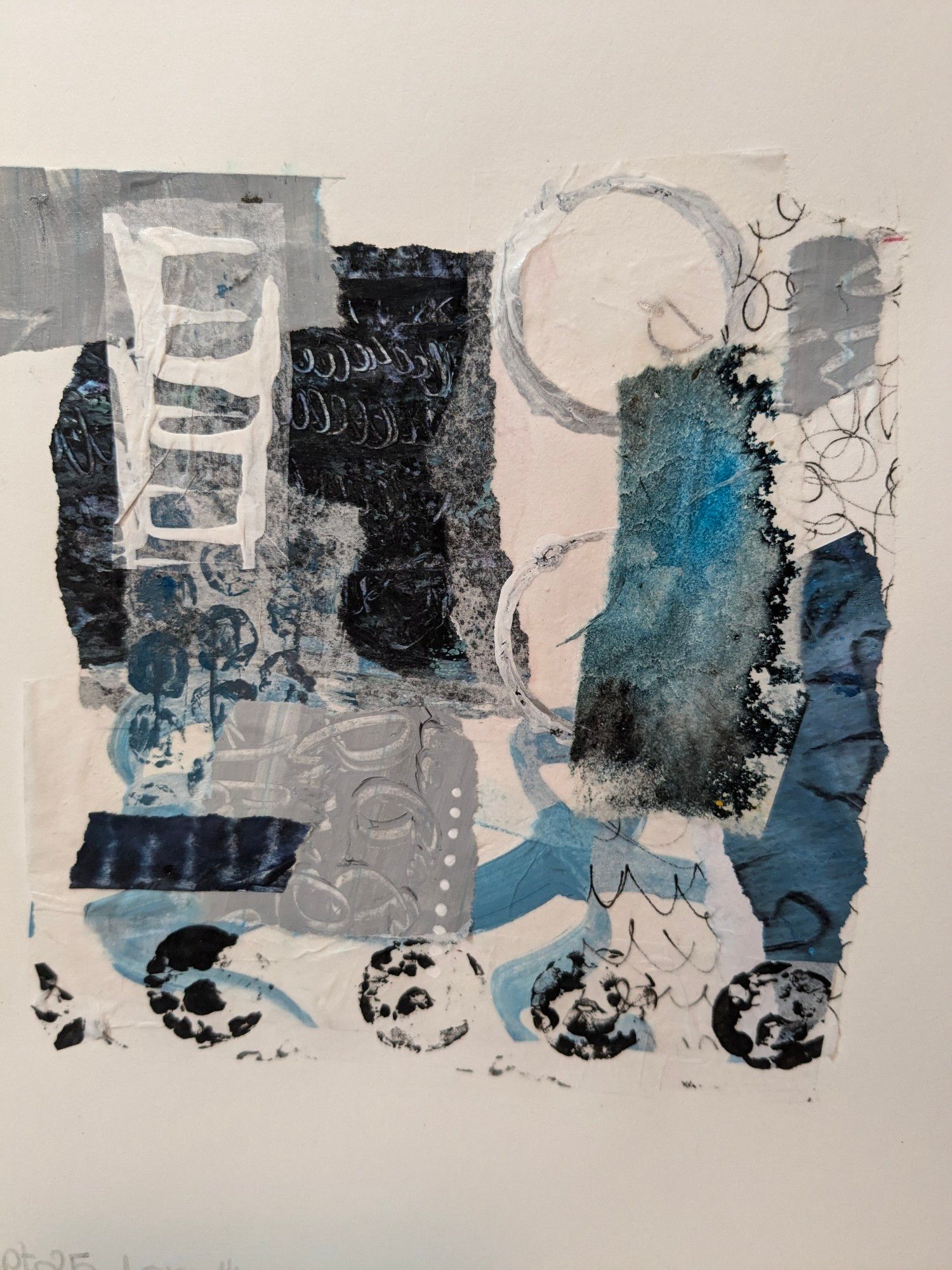 Torn paper collage with textured and torn papers in shades of blue, black and grey with pieces of asemic writing