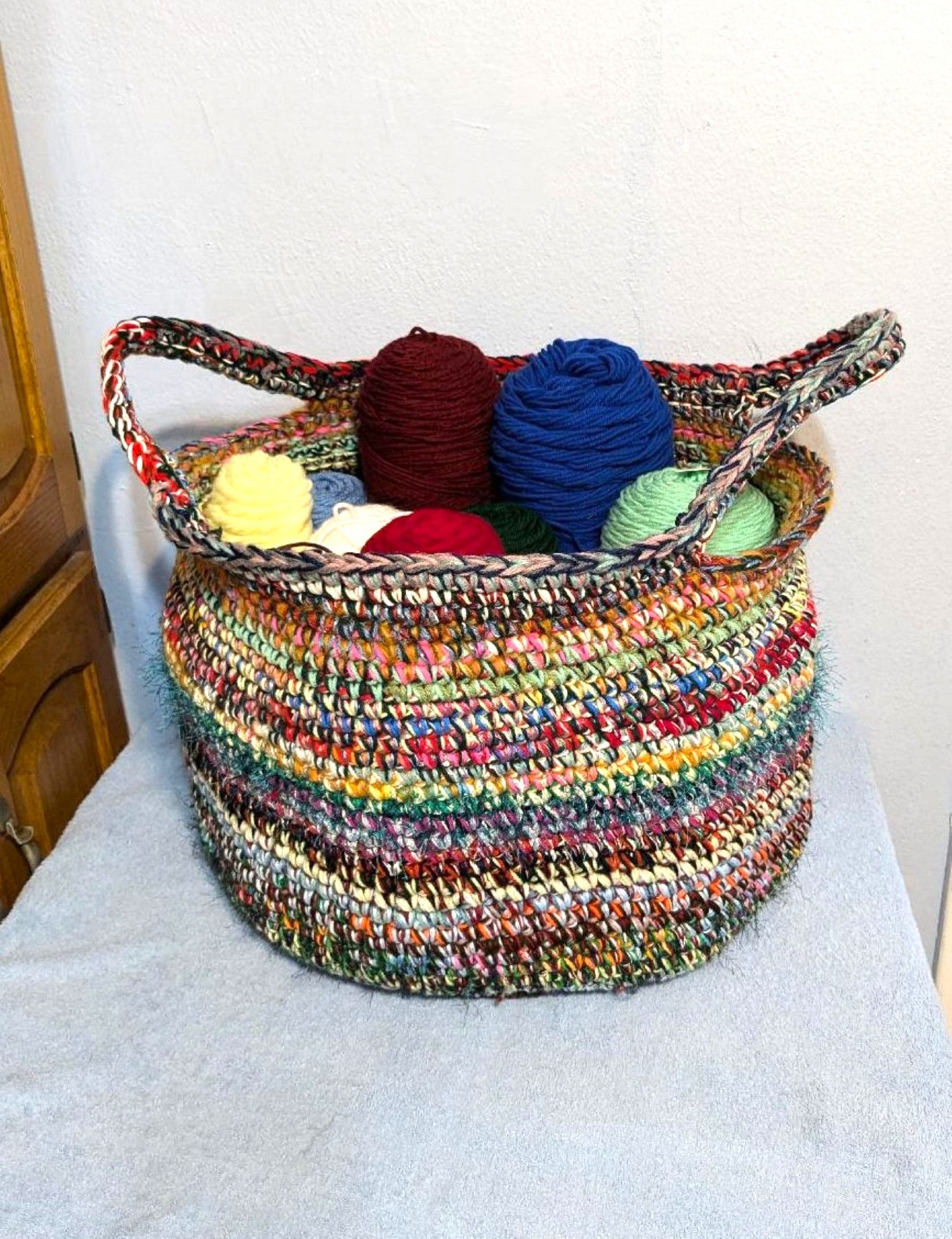 Large multi colored basket. Made by crocheting many different strands of yarn  of different fibers and textures held together. Size approximate 17 inches wide by 13 inches tall. Has two handles on each side. Very strong.