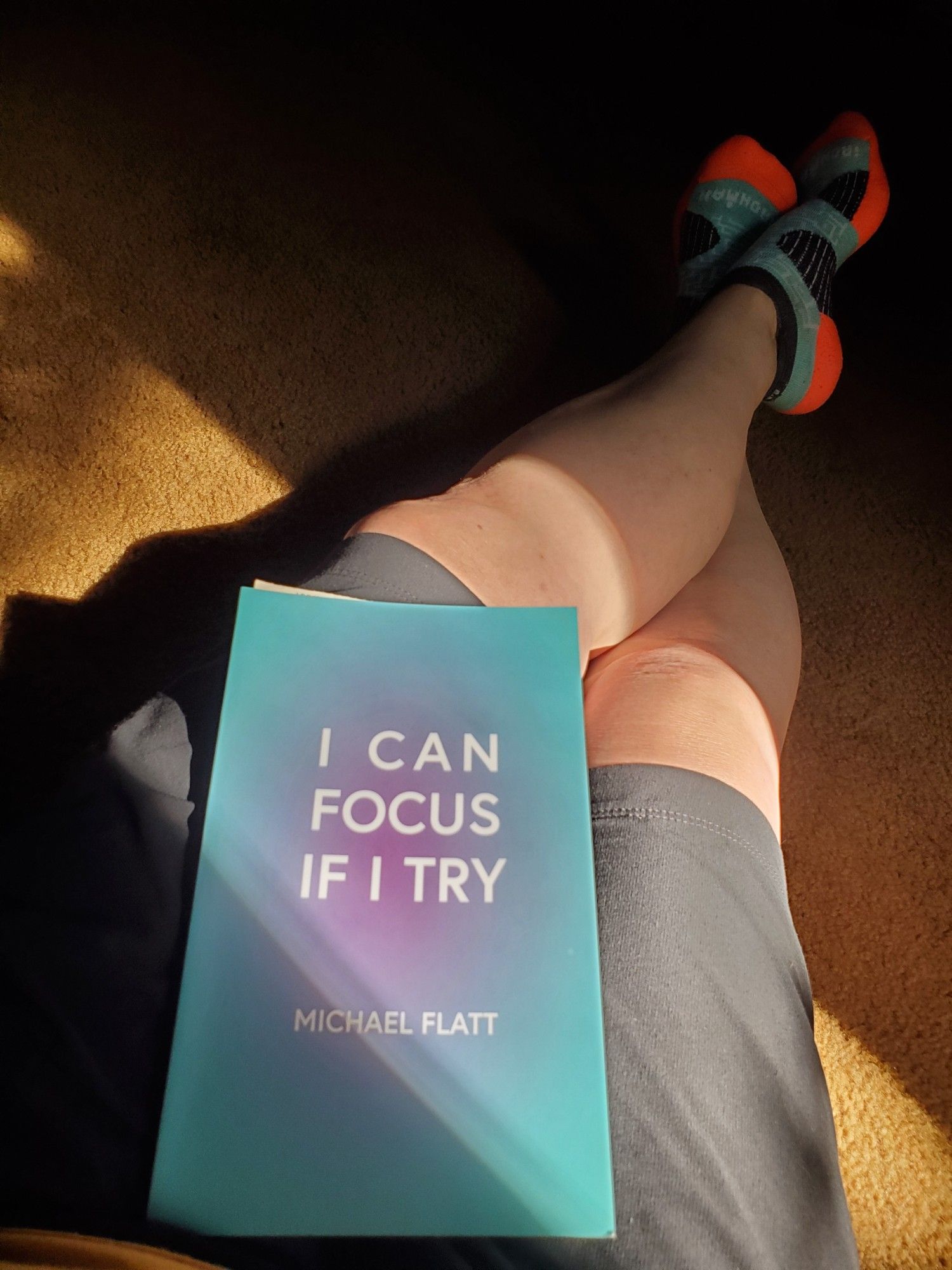 Poetry collection I Can Focus If I Try by Michael Flatt (knife | fork | book) sits in my lap. My legs stretch out, my feet are shod in aqua and neon orange socks. Afternoon light stretches across the rug.