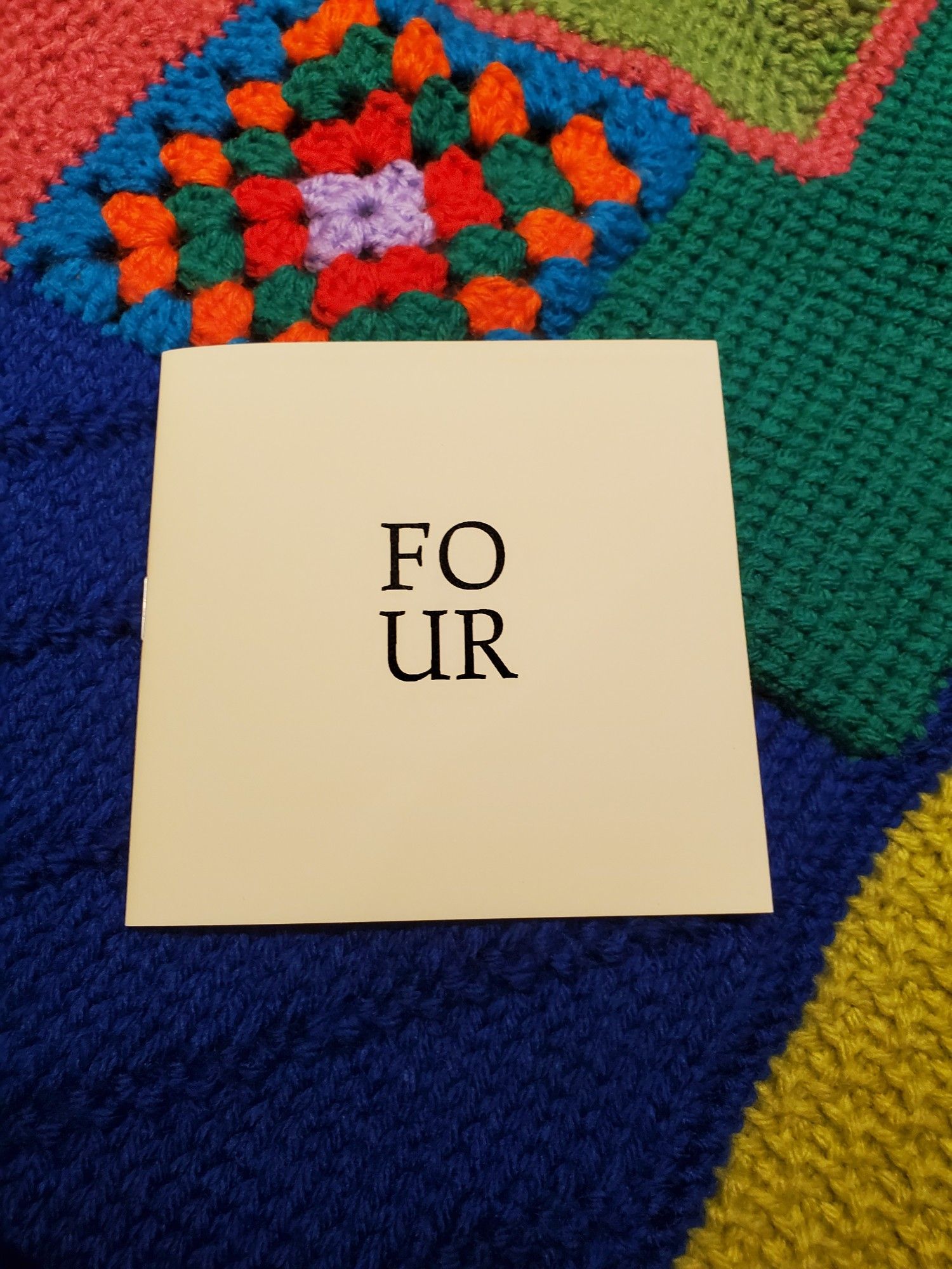 Special edition poetry chapbook FO/UR by Jo Ianni (Apt 9 Press) sits atop a colourful crocheted afghan