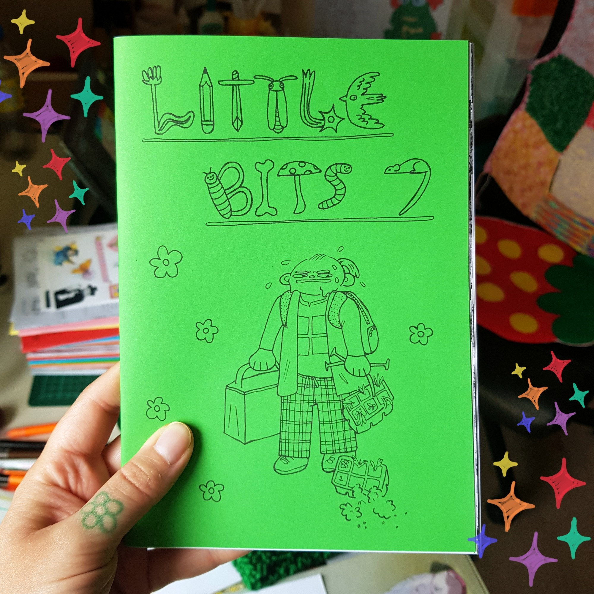 a green copy of a zine called Little Bits 7. there is a drawing of a person looking sweaty and disgruntled they're holding some plant trays that have fallen and one has hit the ground and spilt out.