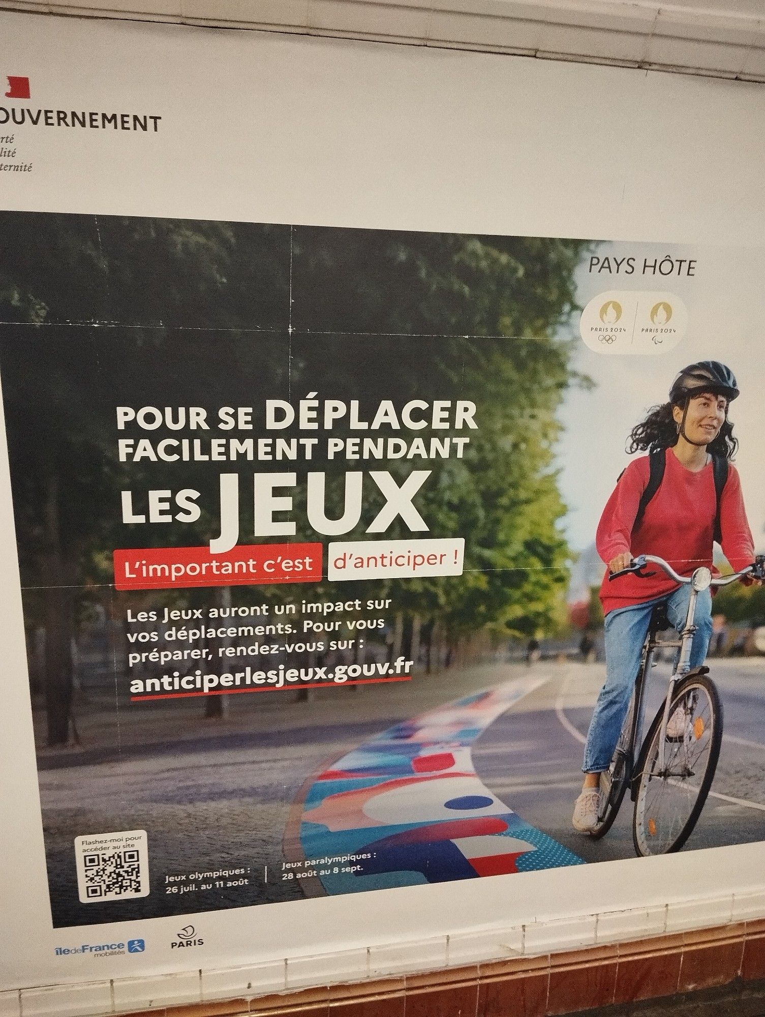 Publicité dans le métro pour les JO avec écrit "Pour se déplacer facilement pendant les jeux, l'important c'est d'anticiper ! Les jeux auront un impact sur vos déplacements. Pour vous préparer, rendez vous sur : anticiper les jeux point gouv point fr"