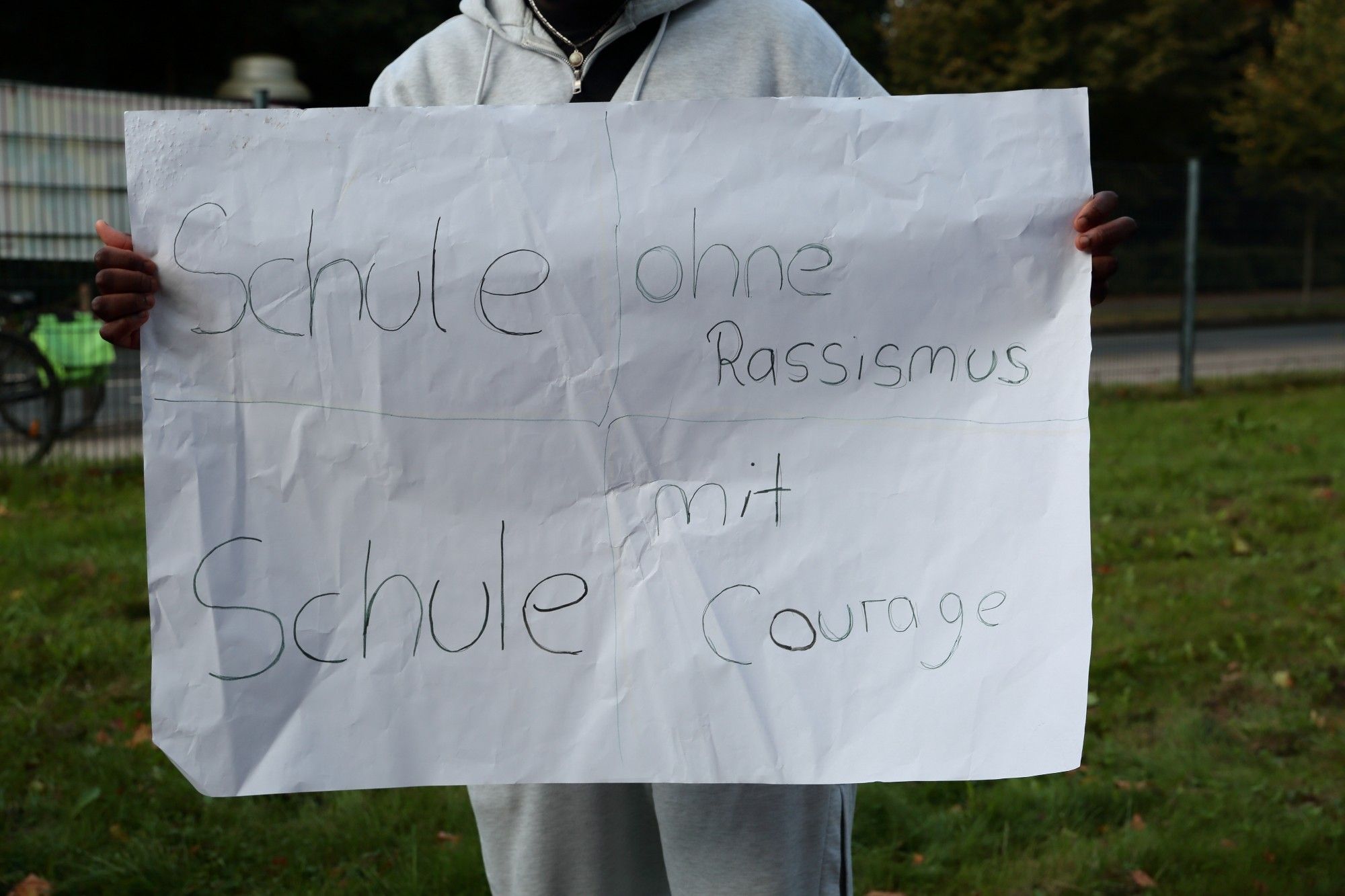 Ein Schüler hält Schild mit "Schule ohne Rassismus.  Schule mit Courage"