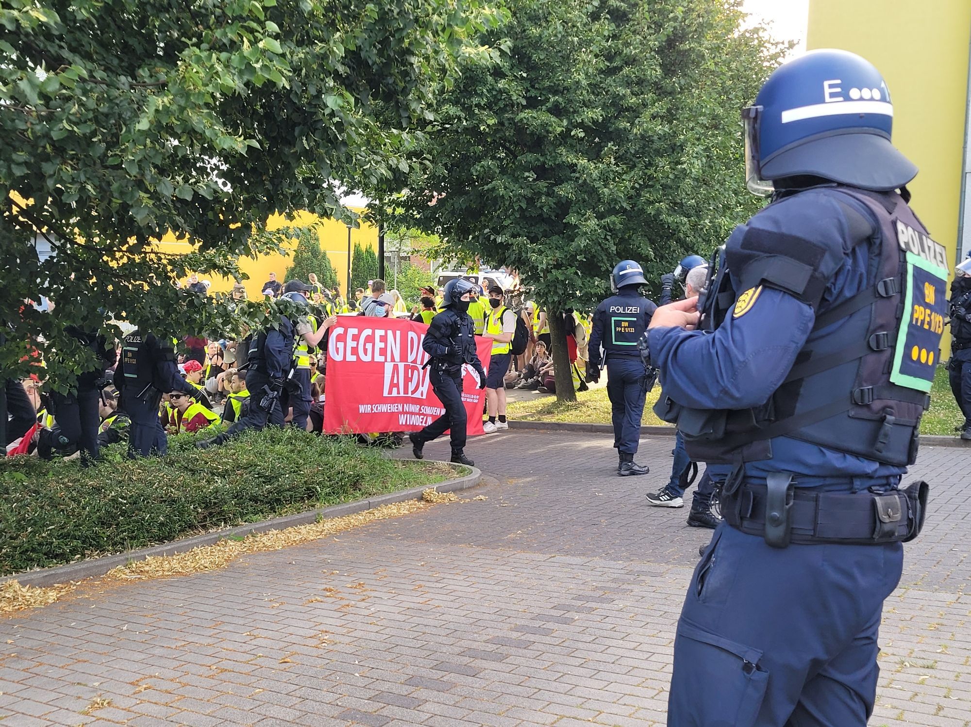 Polizisten klettern über Sitzende und sammeln sich auf dem Hotelparkplatz