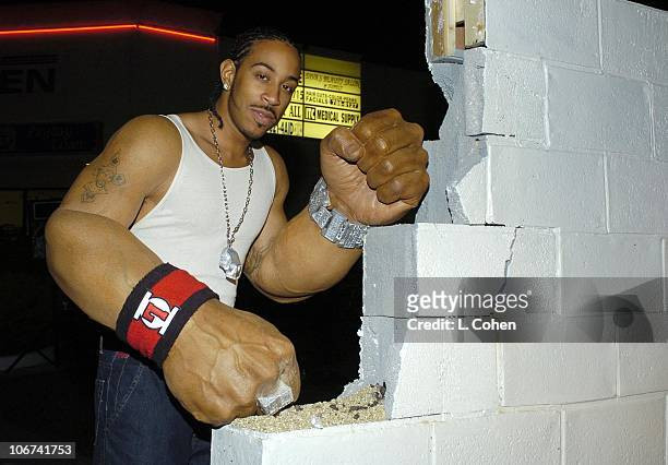 Ludacris pretending to punch through a wall with his giant arm prosthetics