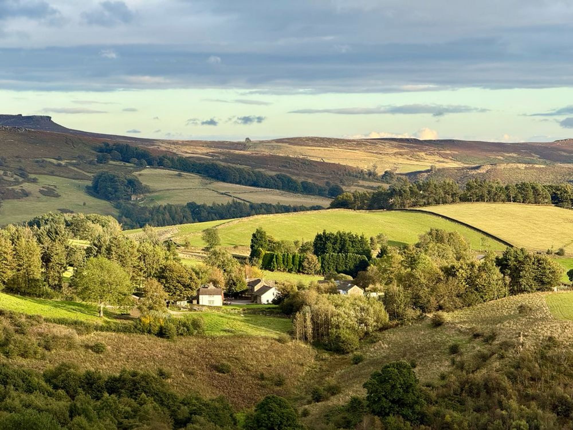 A farmhouse sitting a med rolling hills in the evening sunlight