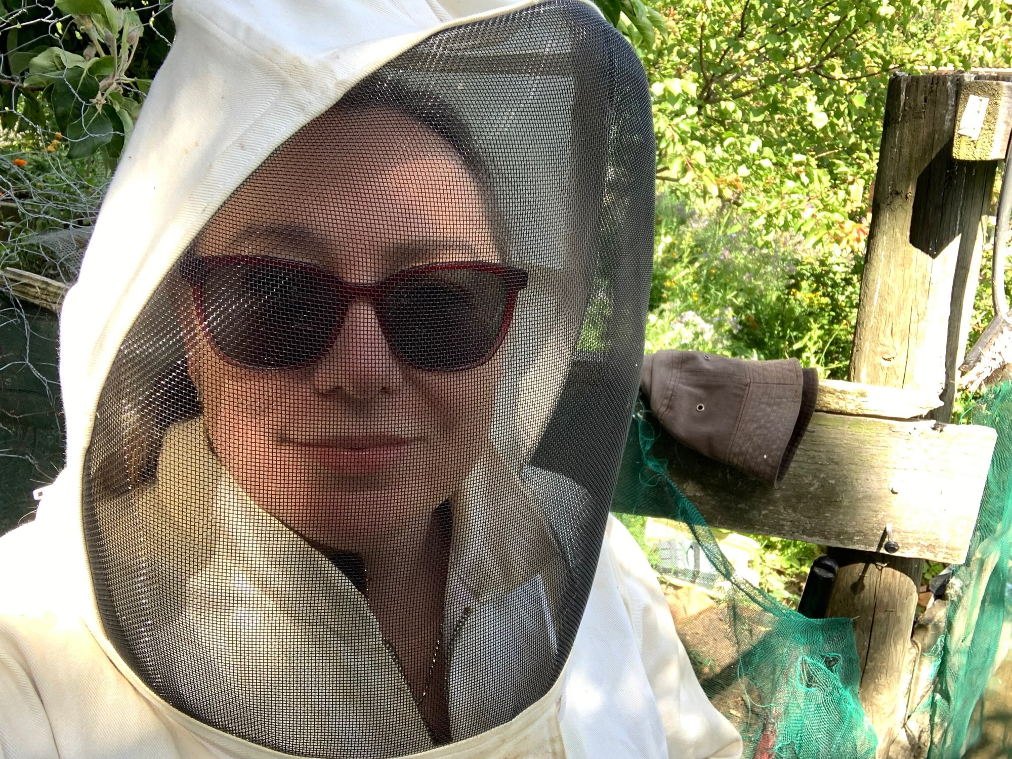 Heather in a bee suit and sunglasses at a farm.