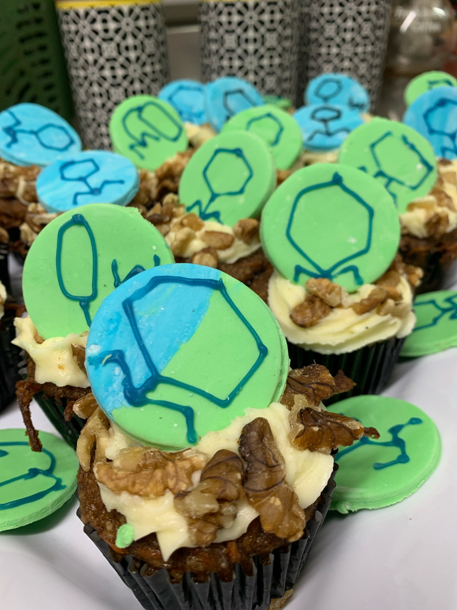 Carrot cake cupcakes with blue and green fondant disks with blue phages in icing.