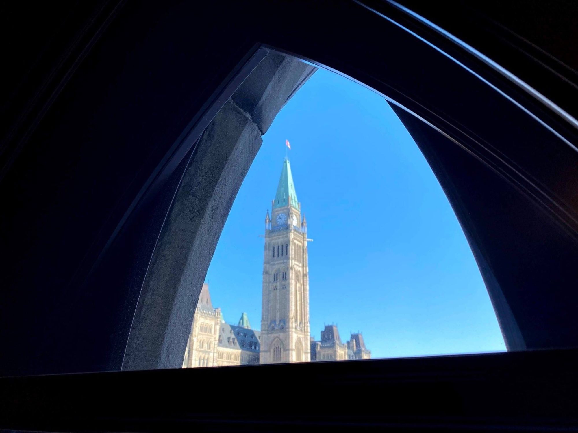 The Peace Tower on Parliament Hill in Ottawa seen through a gothic window in West Block of parliament. 