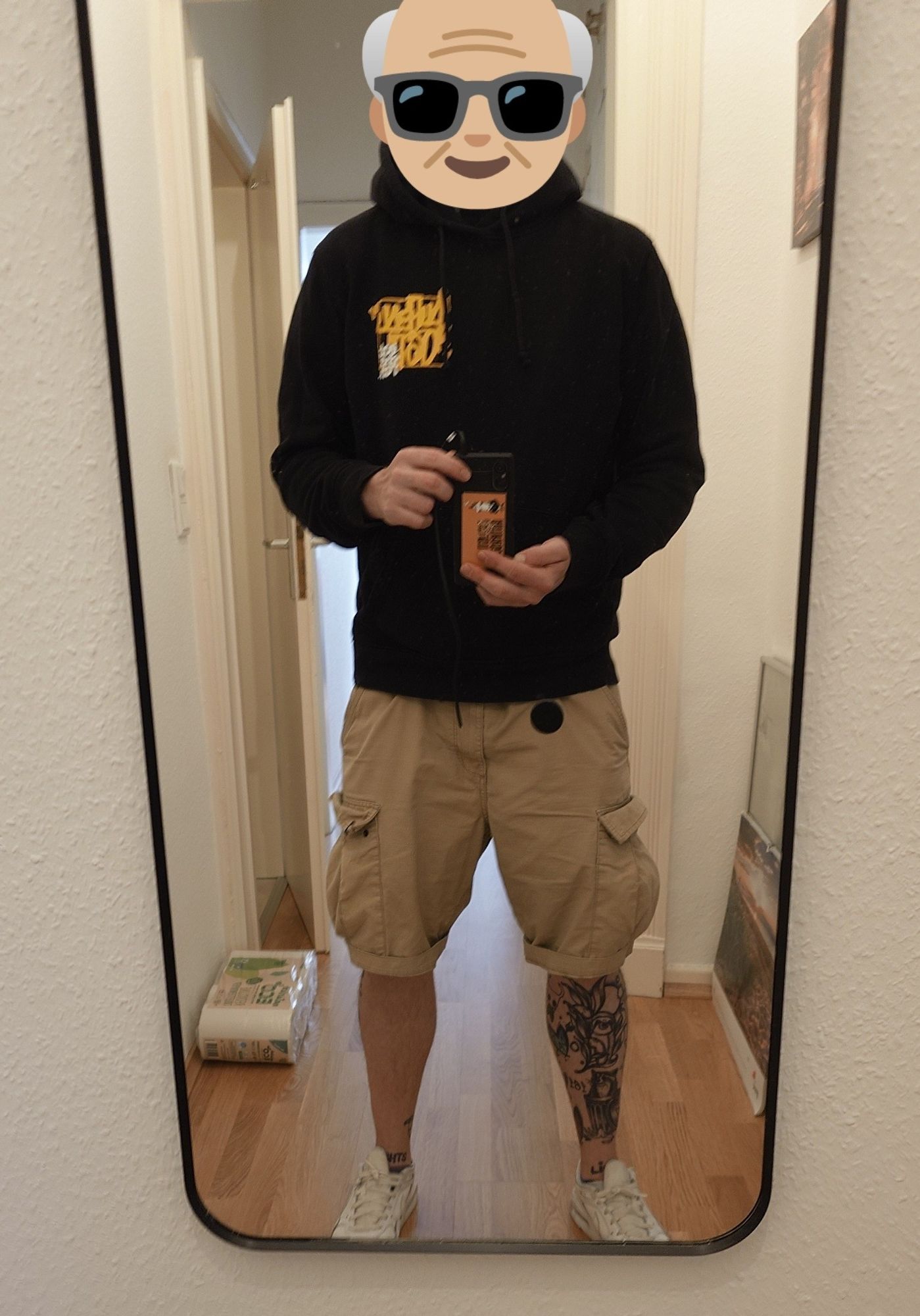 Spiegel Selfie, Typ mit Sandfarbenen Shorts, weißen Airmax 90 und schwarzem Eat the rich Hoodie. Statt des Kopfes sieht man ein Opa-Emoji mit Sonnenbrille