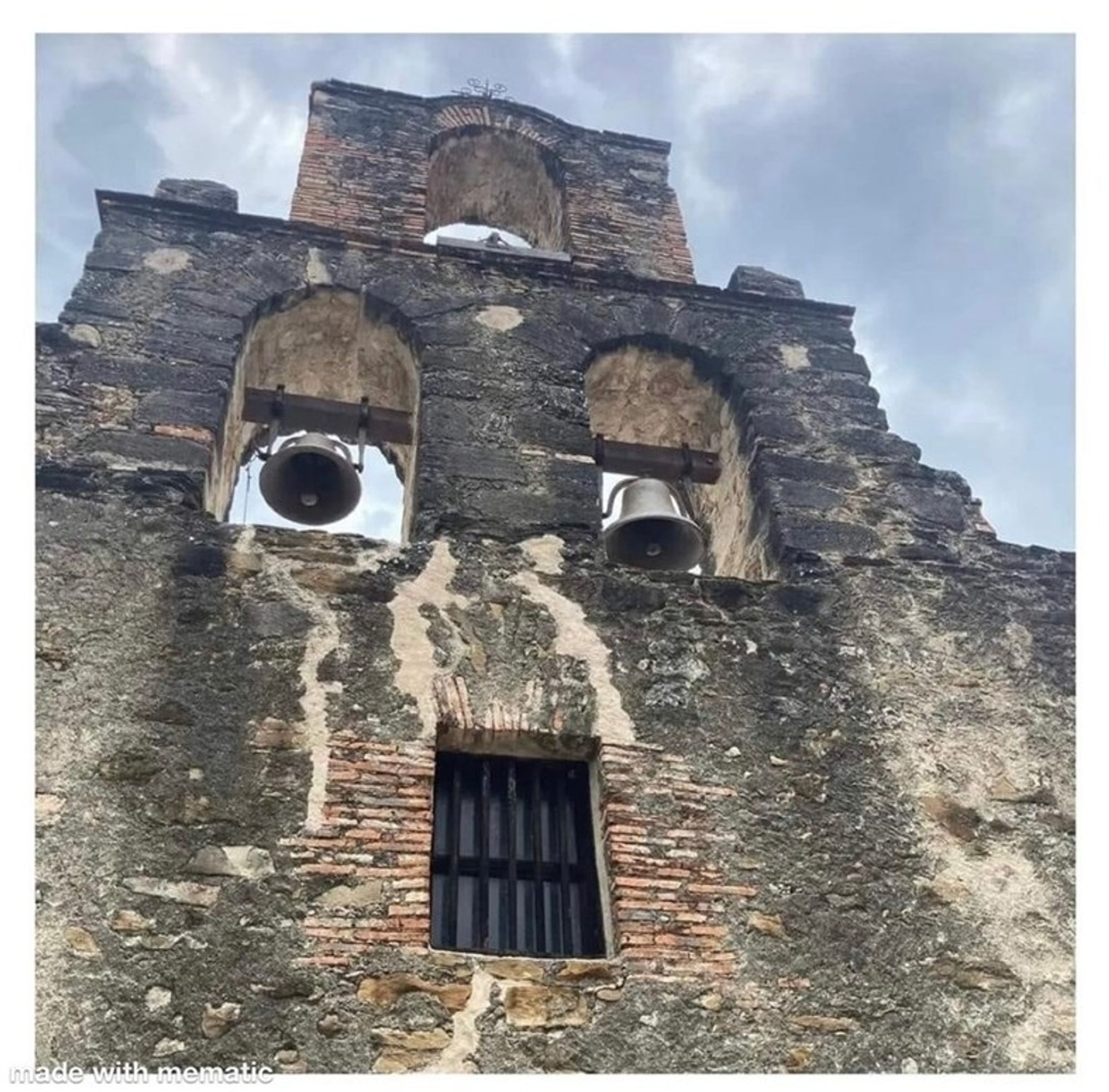 Mauer eines alten Kirchengebäudes. Oben sind zwei Fenster mit entgegengesetzt schwingenden Glocken, sie sehen aus wie komische Augen. Darunter ein vergittertes Fenster das wirkt wie ein Mund. Die Wand ist sehr verwittert, an einigen Stellen fehlt Putz. Es sieht insgesamt wie ein sehr derangiertes Gesicht aus