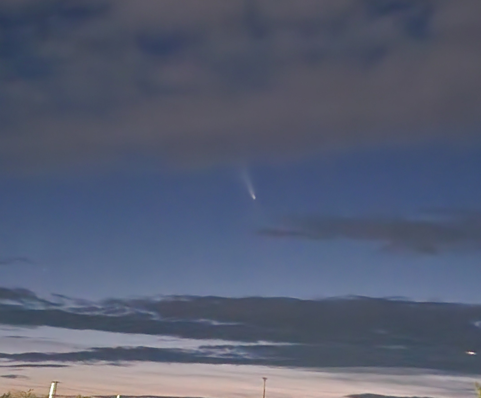 A comet streaks from behind a bank of clouds