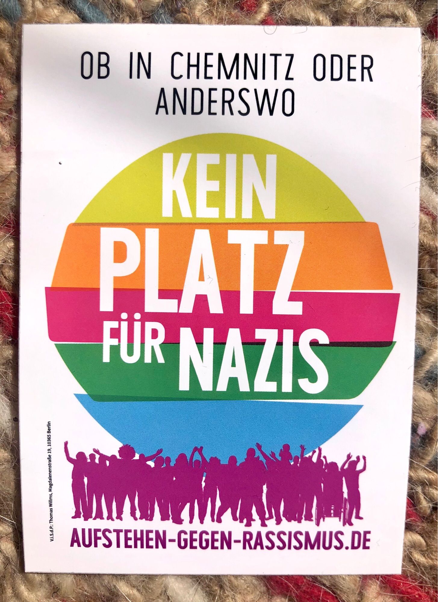 Aufkleber Text: Ob in Chemnitz oder anderswo, kein Platz für Nazis. Dahinter ein Kreis in Regenbogenfarben. Unter dem Kreis Silhouette einer Menschenansammlung, darunter Text: aufstehen-gegen-rassismus.de