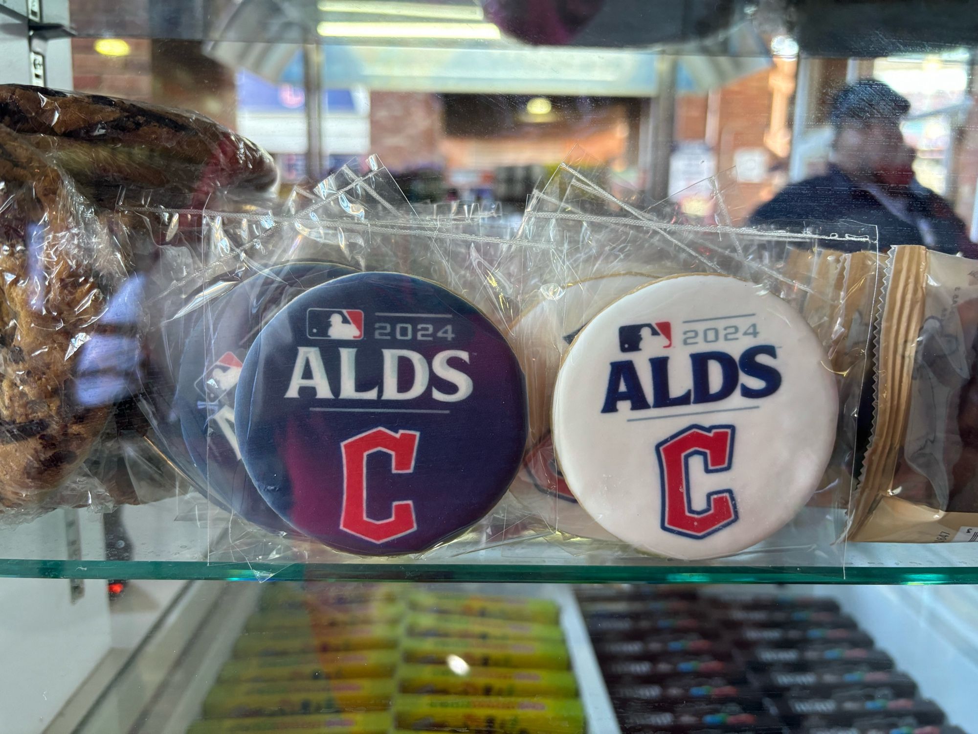 Frosted cookies on a glass shelf, one blue one white, showing the MLB 2024 ALDS and Cleveland Guardians “Diamond” C logos.