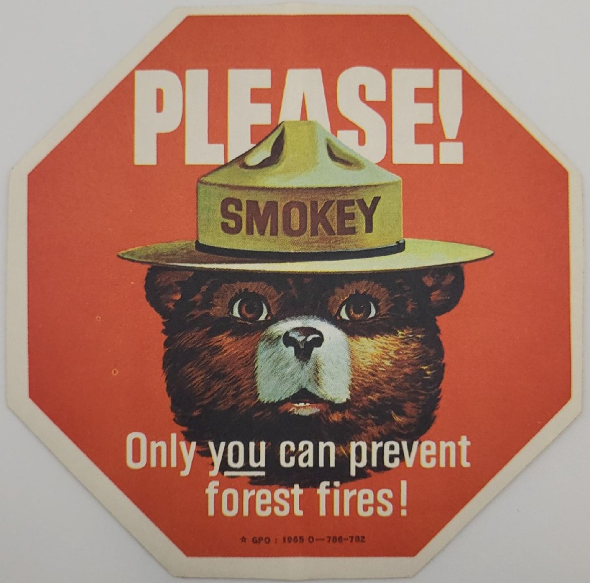 Old Smokey the Bear image.

Smokey's kindly face is partially shadowed by his hat. He's looking directly at the viewer with his kind eyes, his mouth slightly open as if he's speaking directly to me from that disembodied head on the red background, looking very much like a stop sign.

The text says, "PLEASE! Only you (and the "you" is underlined to drive that point home) can prevent forest fires!"