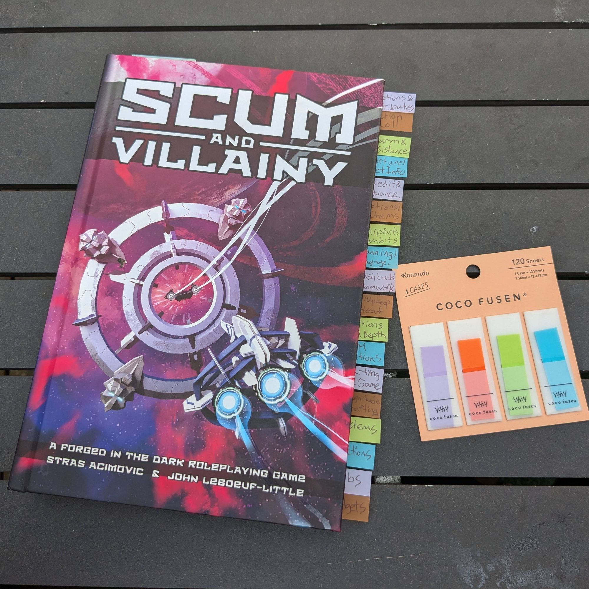 The Scum and Villainy TTRPG rule book with several sticky note tags along the edge. A pack of blank sticky tags.