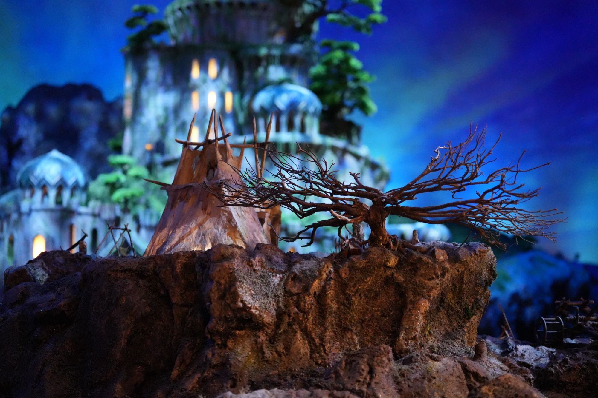 A shot of a bigature made for a fantasy film. In the foreground is a teepee and a blurred background of a grand castle like structure