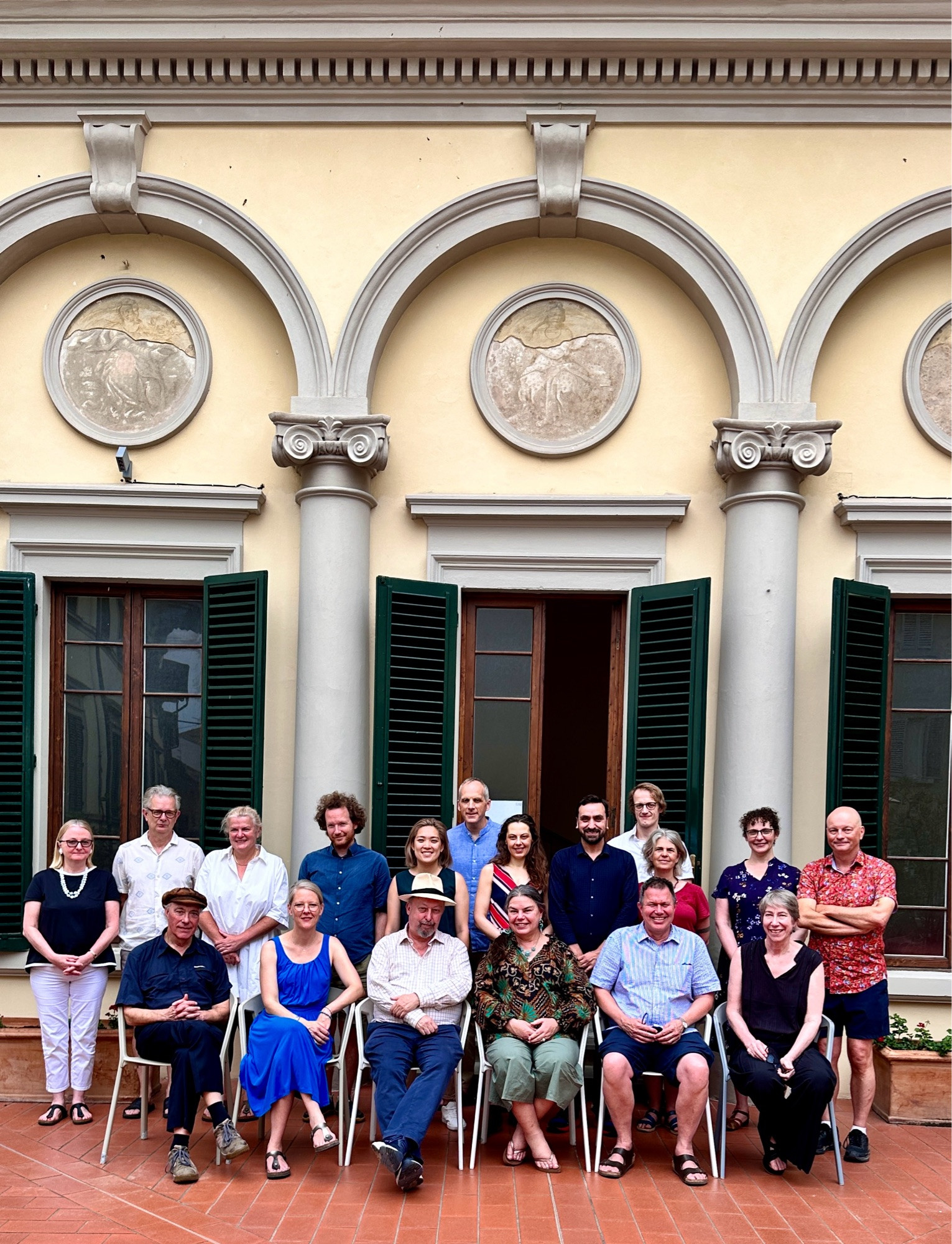 Group picture of people on a terrace with beautiful Italian building in background