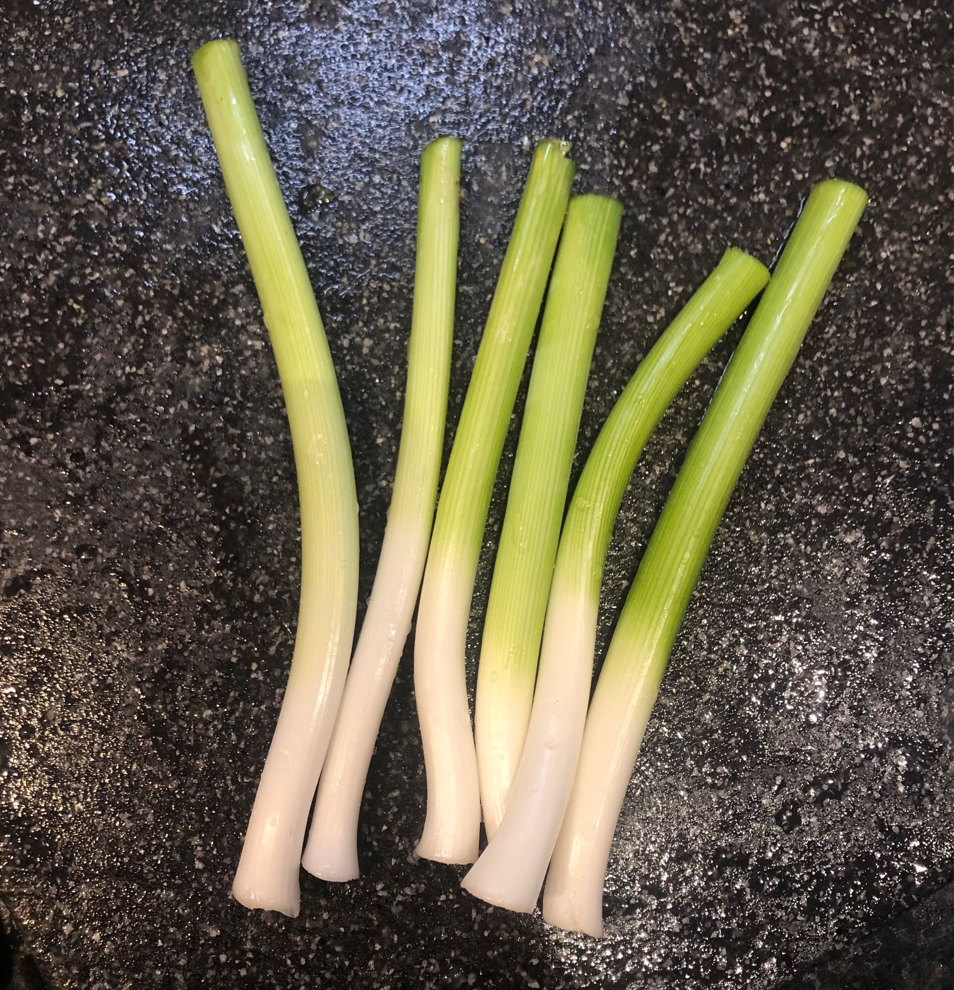 Trimmed baby leeks on a chopping board