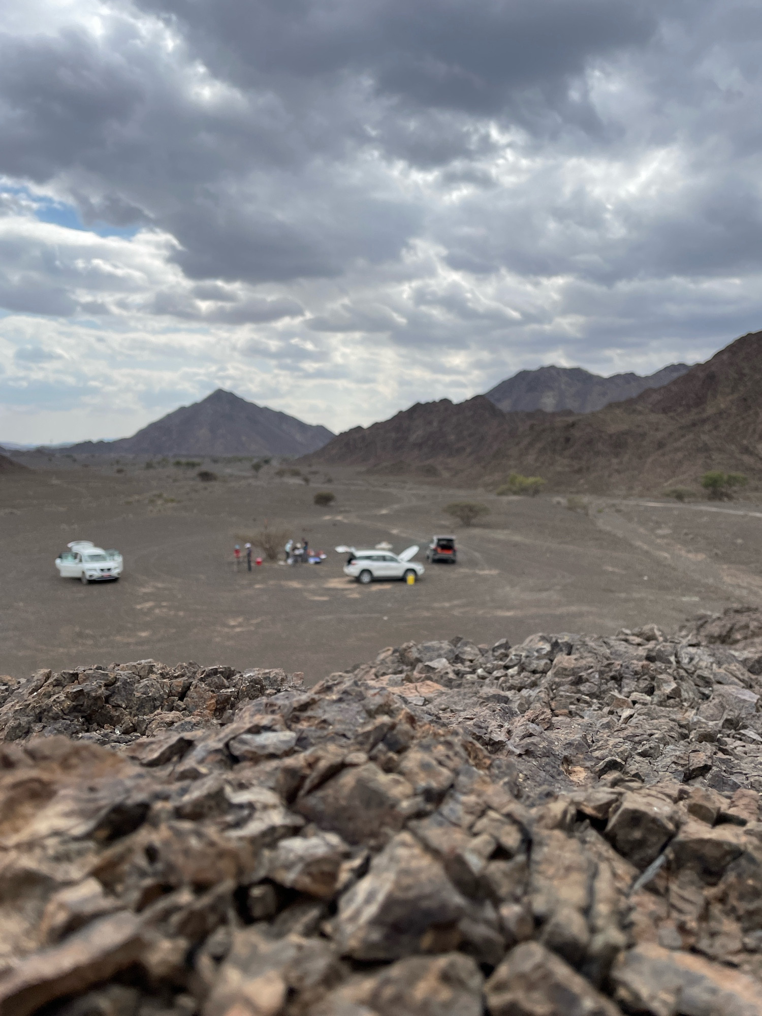 Theee cars parked in the middle of a desert, located at the Semail ophiolite, in Oman.