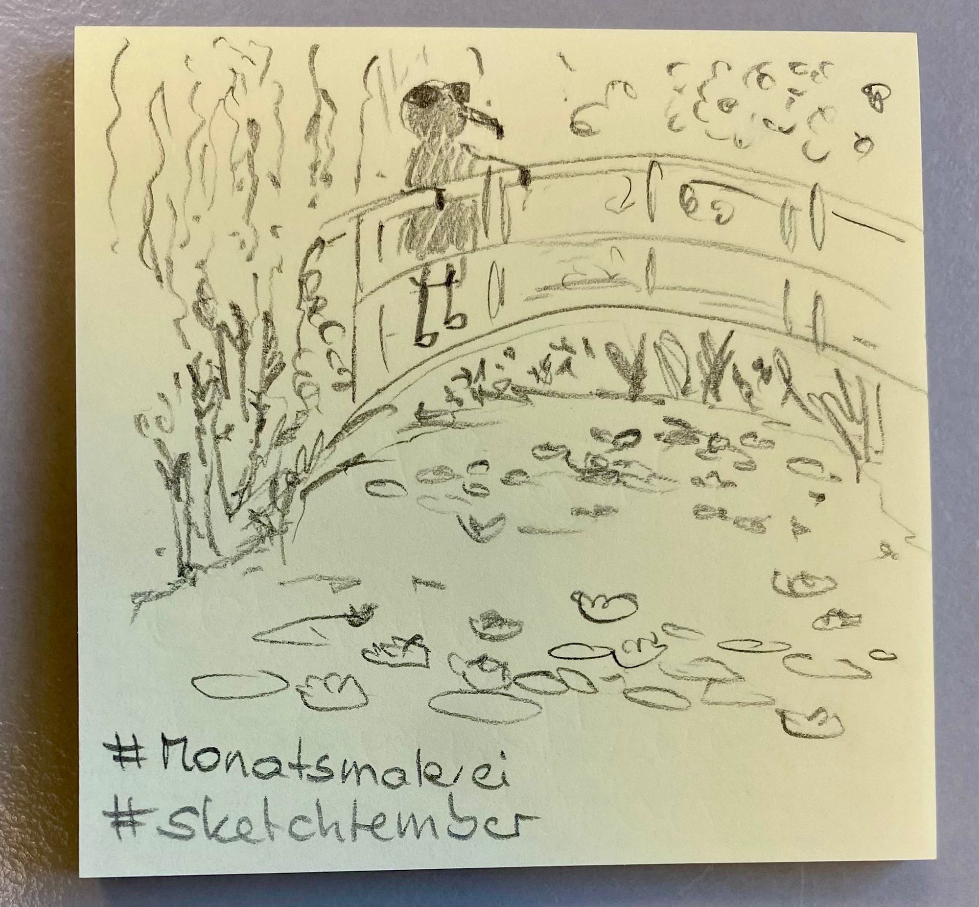 A pencil sketch on a sticky note depicting a fly standing on a bridge overlooking a pond filled with lily pads and surrounded by plants. Includes hashtags "#Monatsmalerei" and "#sketchtember."