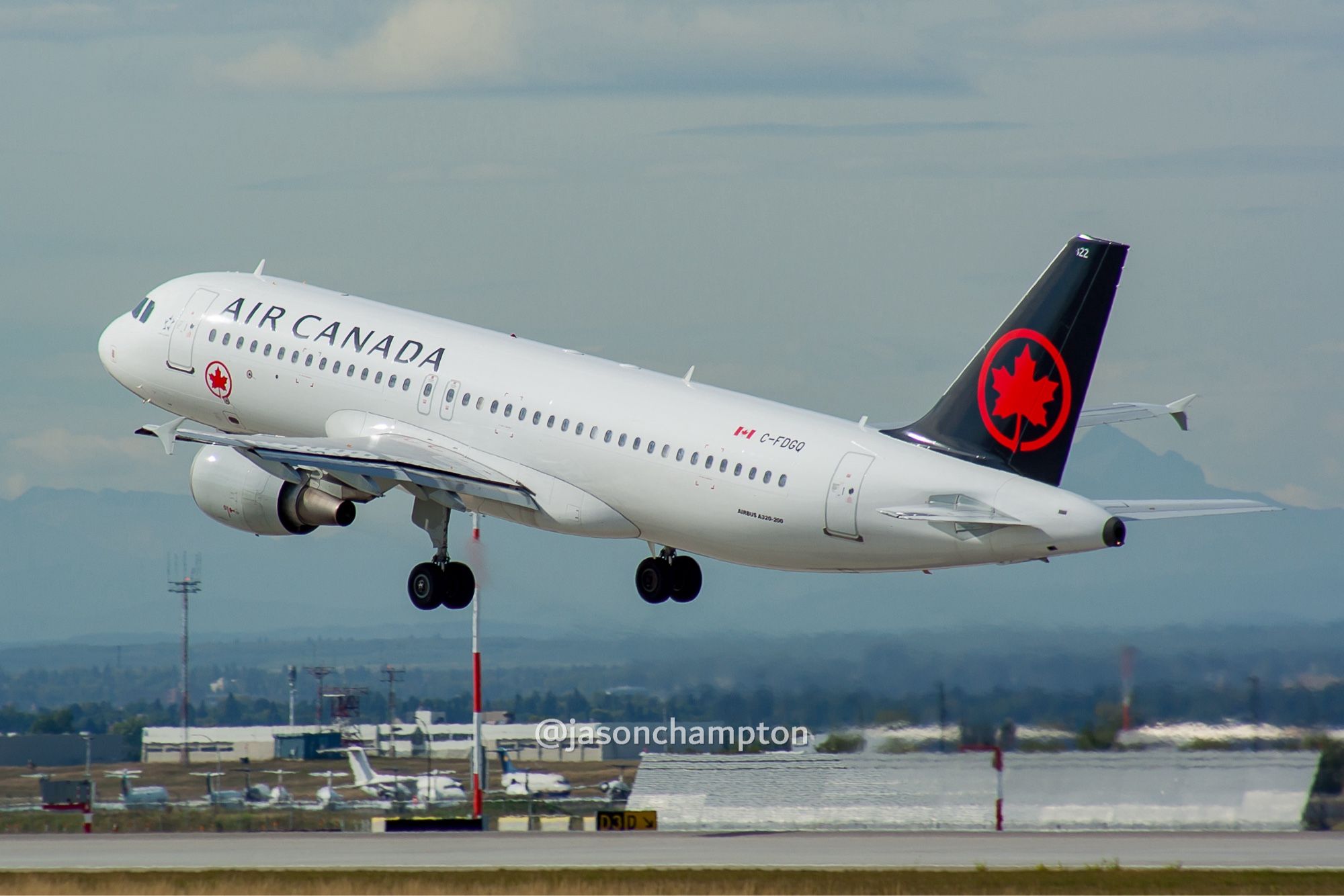 A white jetliner with black tail featuring the Air Canada logo in red taking off