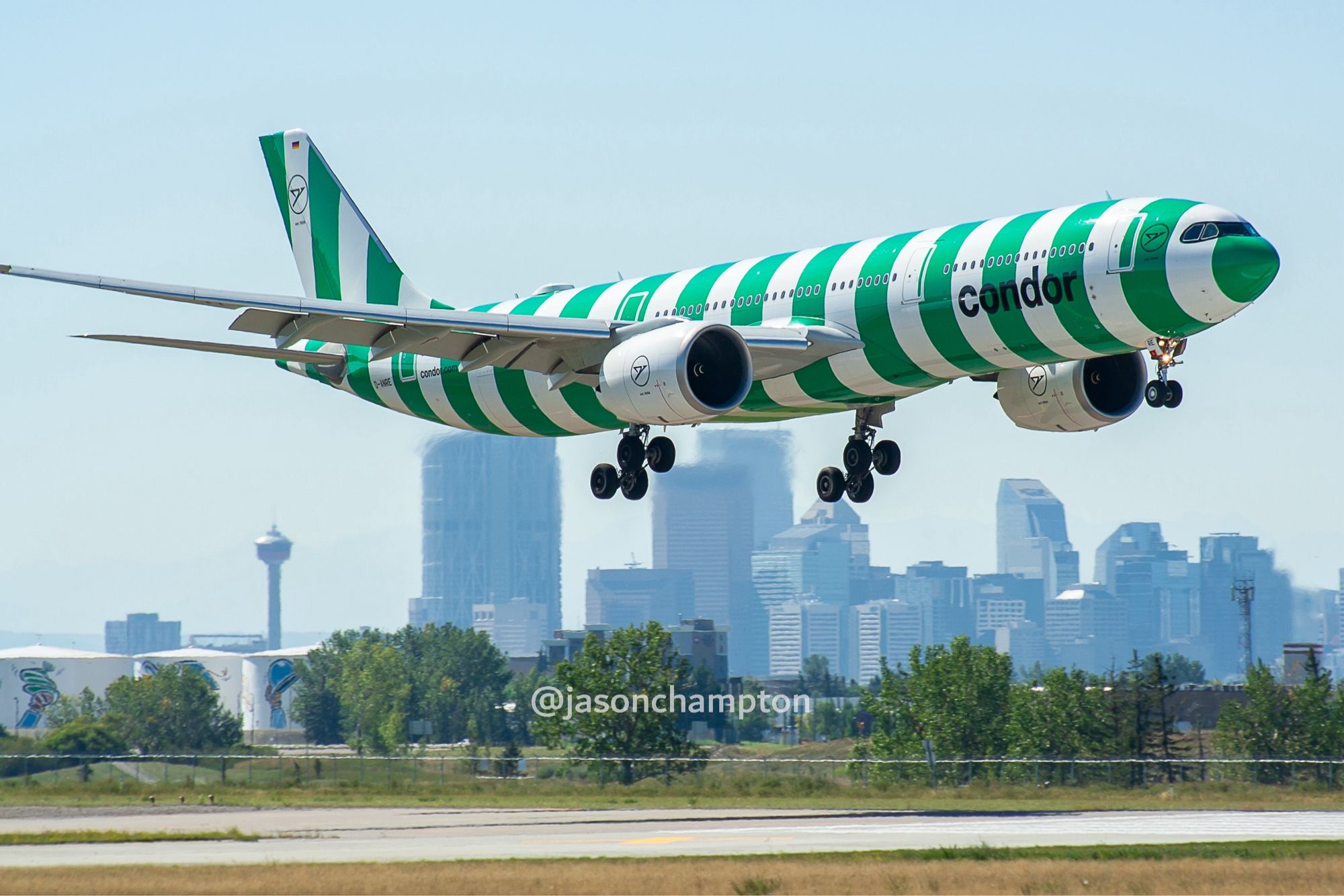 A green and white striped airliner wheels down about to land