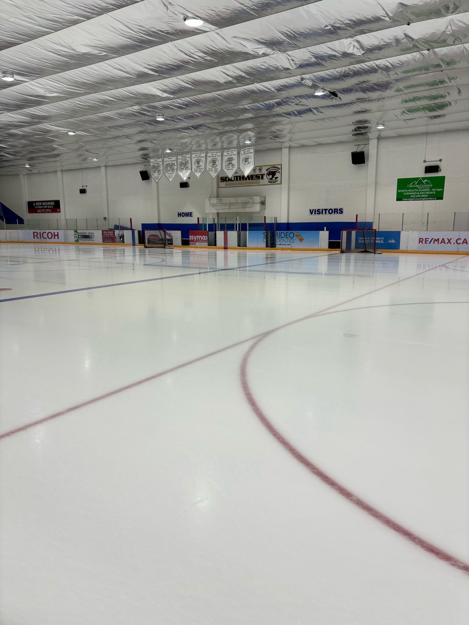 A hockey arena looking across the ice towards the player benches.