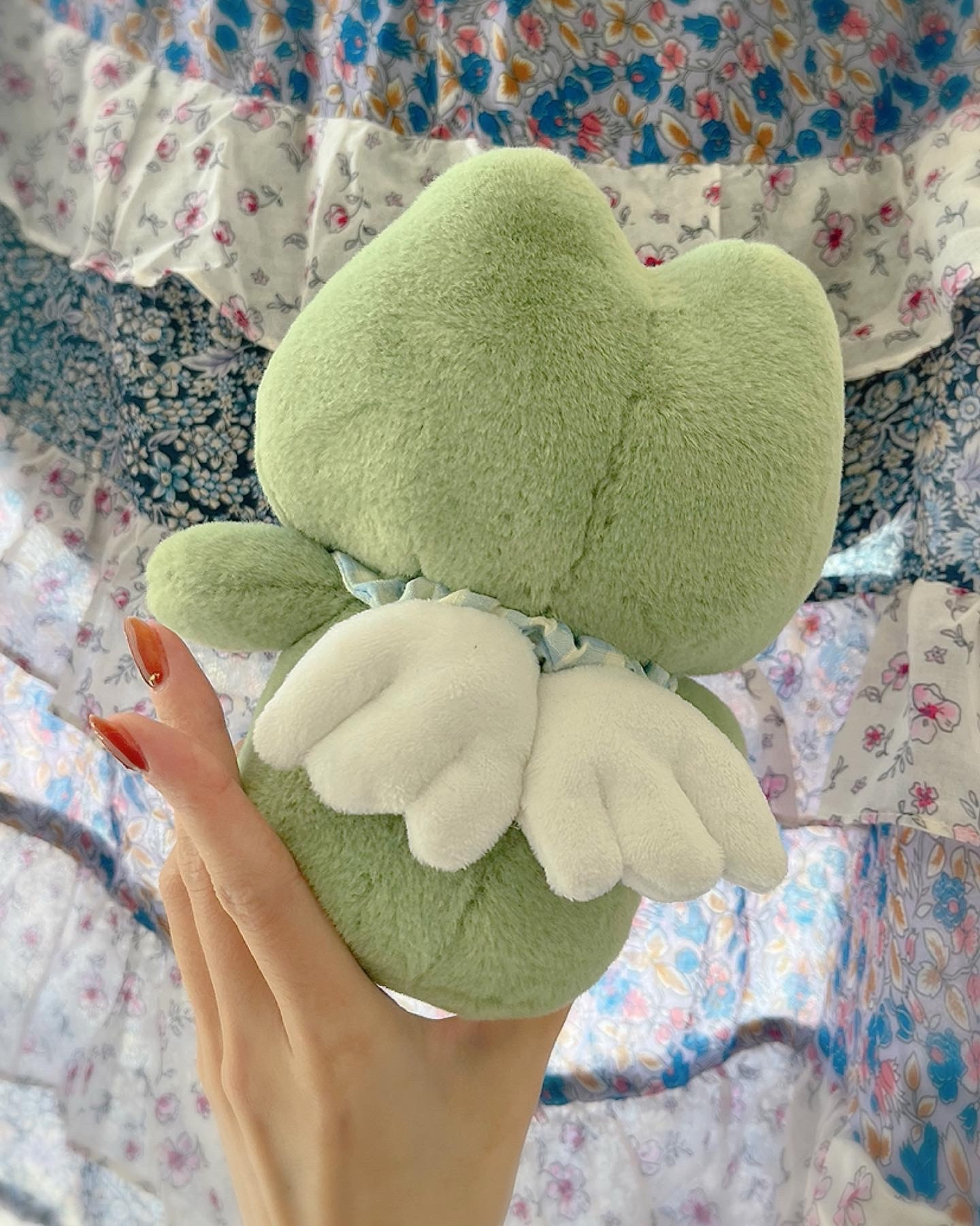 Photo shows the back of the frog plush. It has small angel wings 