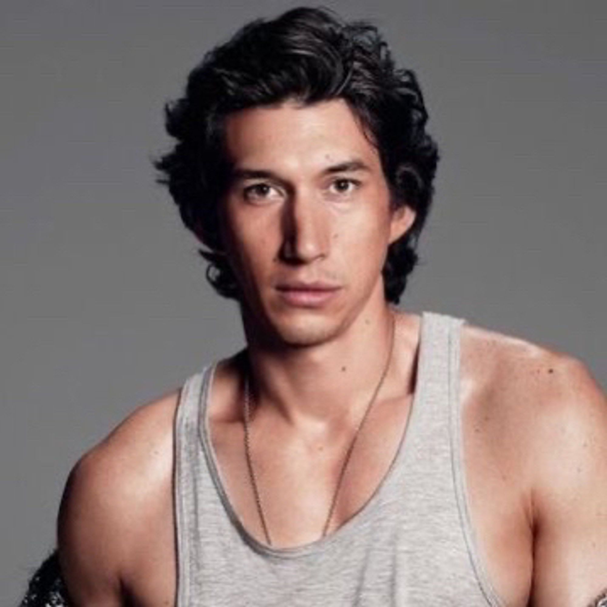 Adam driver with shirt almost curly hair and wearing a chain necklace and grey tank top