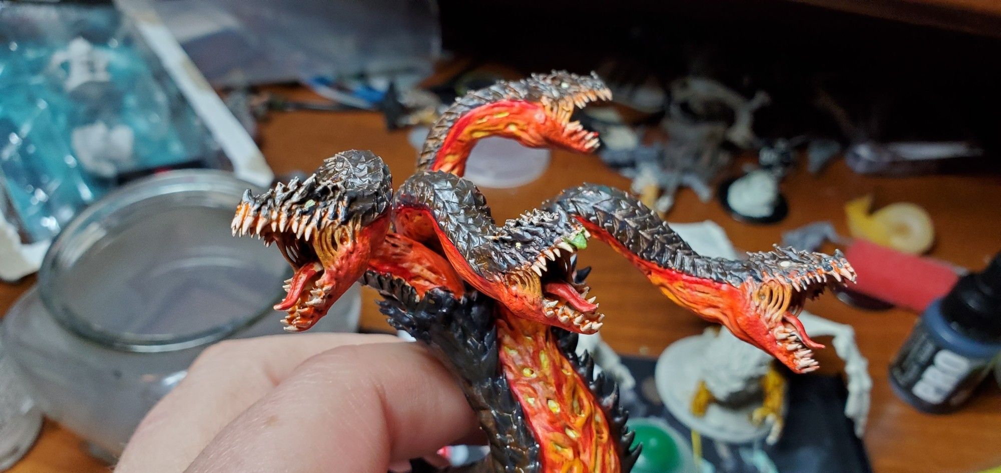 Picture of my painted model Hydra, printed in resin and colored to look like it's crawled out of a volcano. My messy work desk is behind it