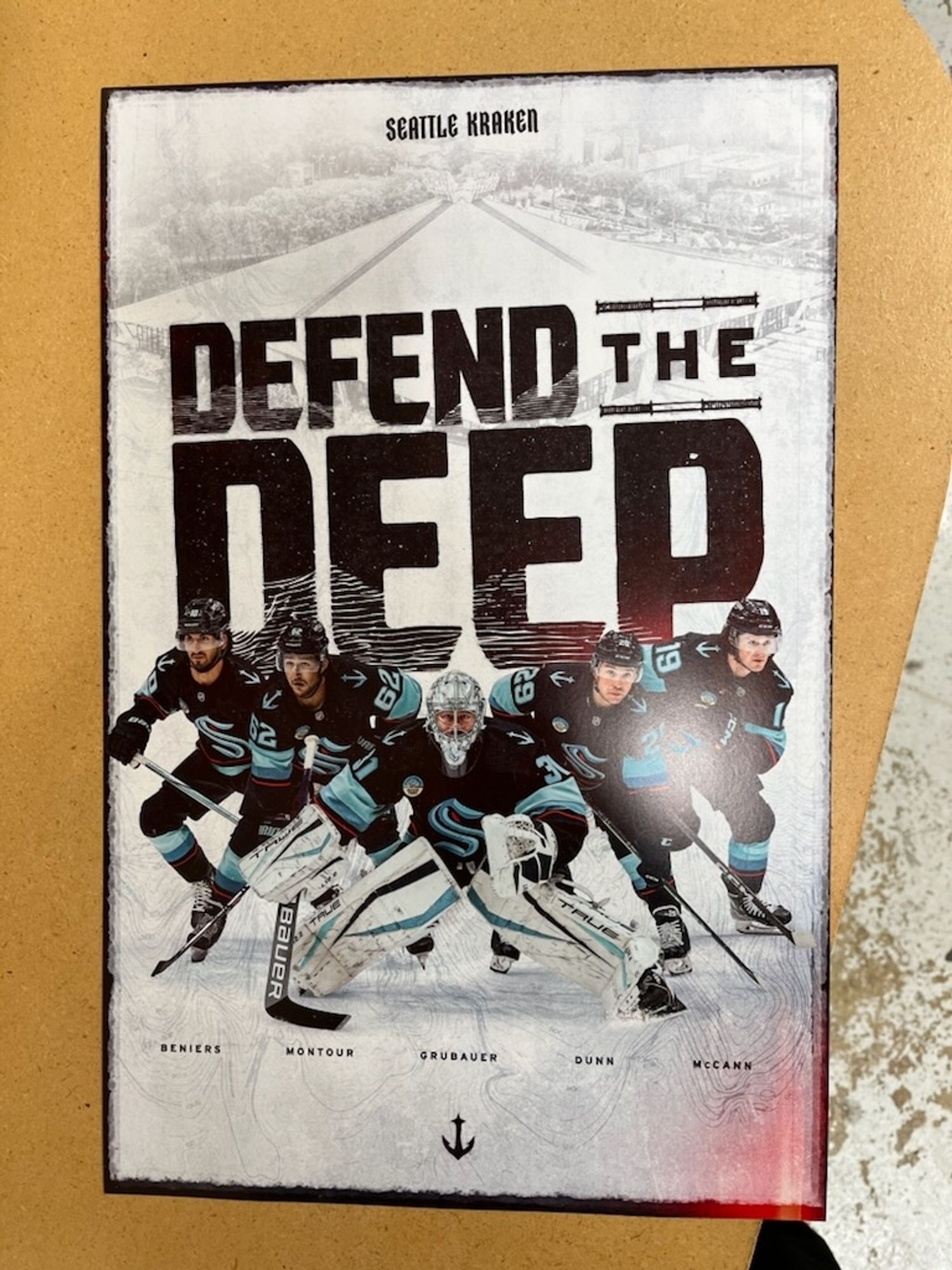 A poster that has a picture of various hockey players in action shots. It reads "Seattle Kraken" at the top, and "Defend the Deep" below that.