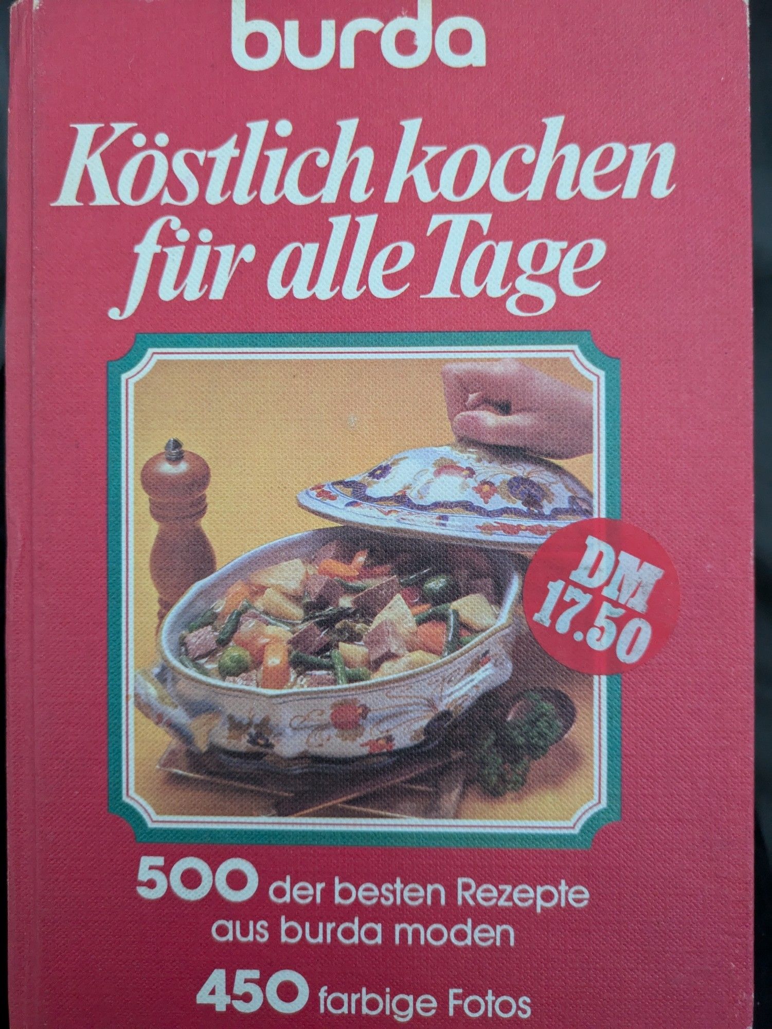 Altes Kochbuch aus dem Burda-Verlag: "Köstlich kochen für alle Tage - 500 der besten Rezepte aus burda moden. 450 farbige Fotos." Abbildung zeigt eine Suppenterrine, deren Deckel von einer Hand gelüftet wird und einen Eintopf aus Rindfleisch,  Kartoffeln, Bohnen und Möhren zum Vorschein bringt. Ein kreisrunder Sticker zeigt den Preis von 17,50 DM.