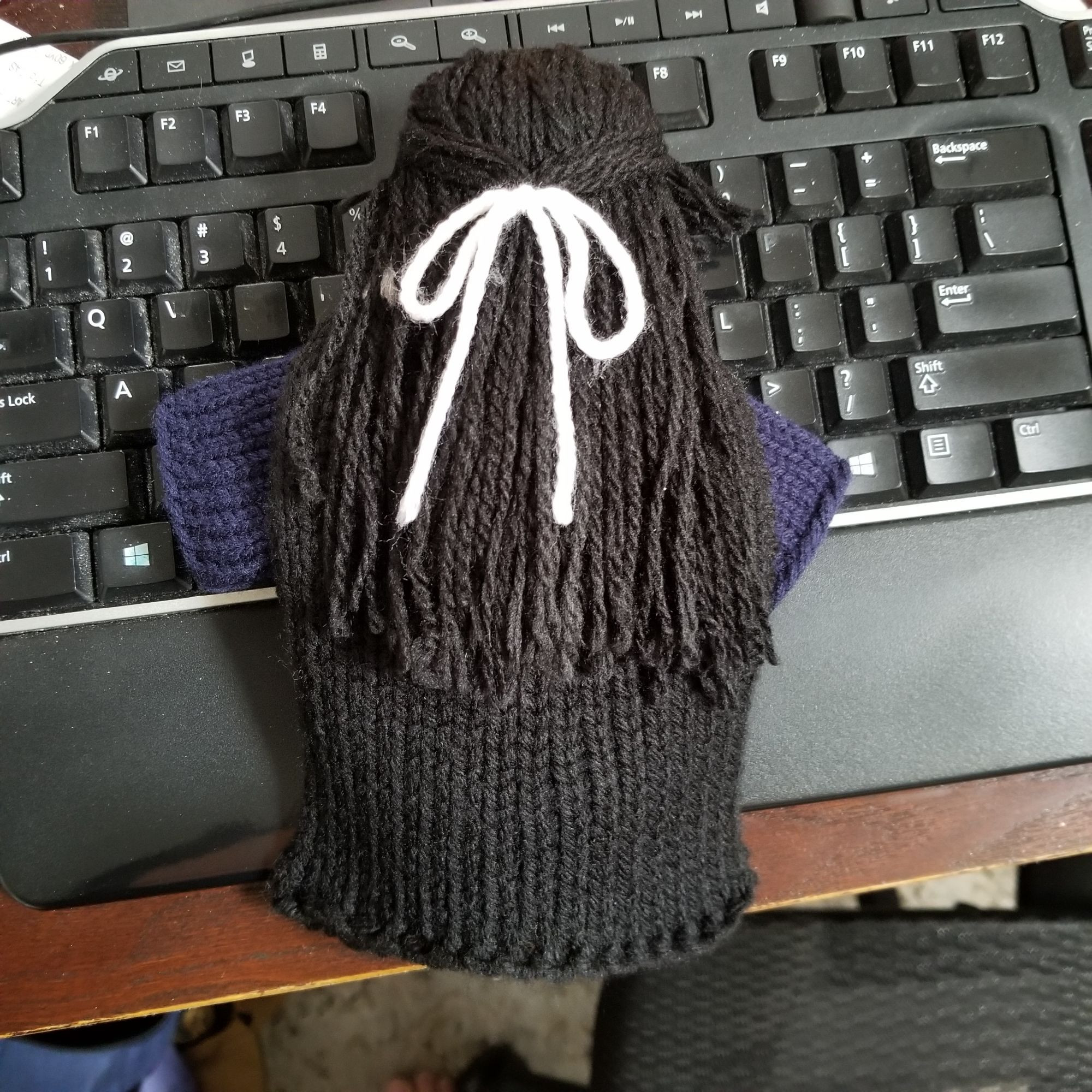 Back view of Cui Buqu doll showing his long black hair tied back with a white ribbon (made of yarn), and his black cape.