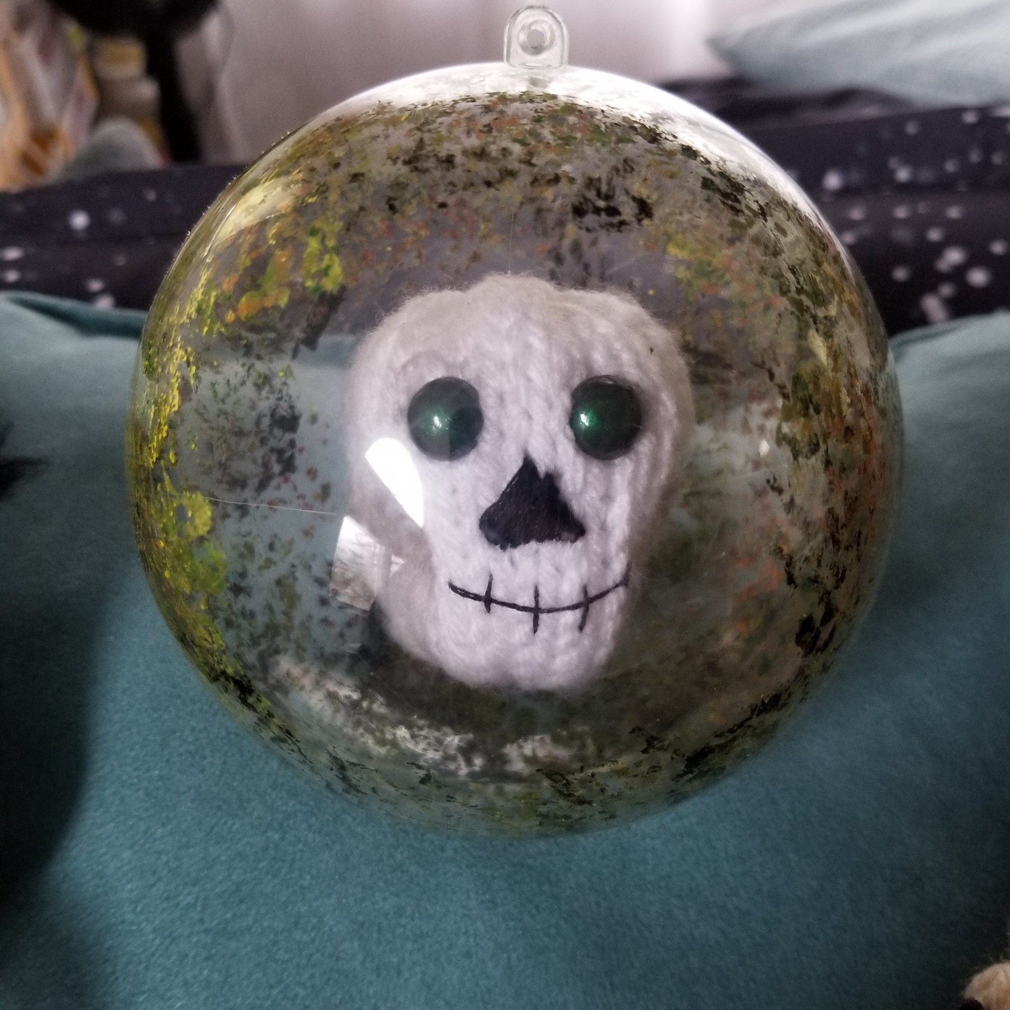 A solo photo of Mort. He is a smiling skull with dark green eyes floating in a plastic ball. The ball is painted to look mossy.