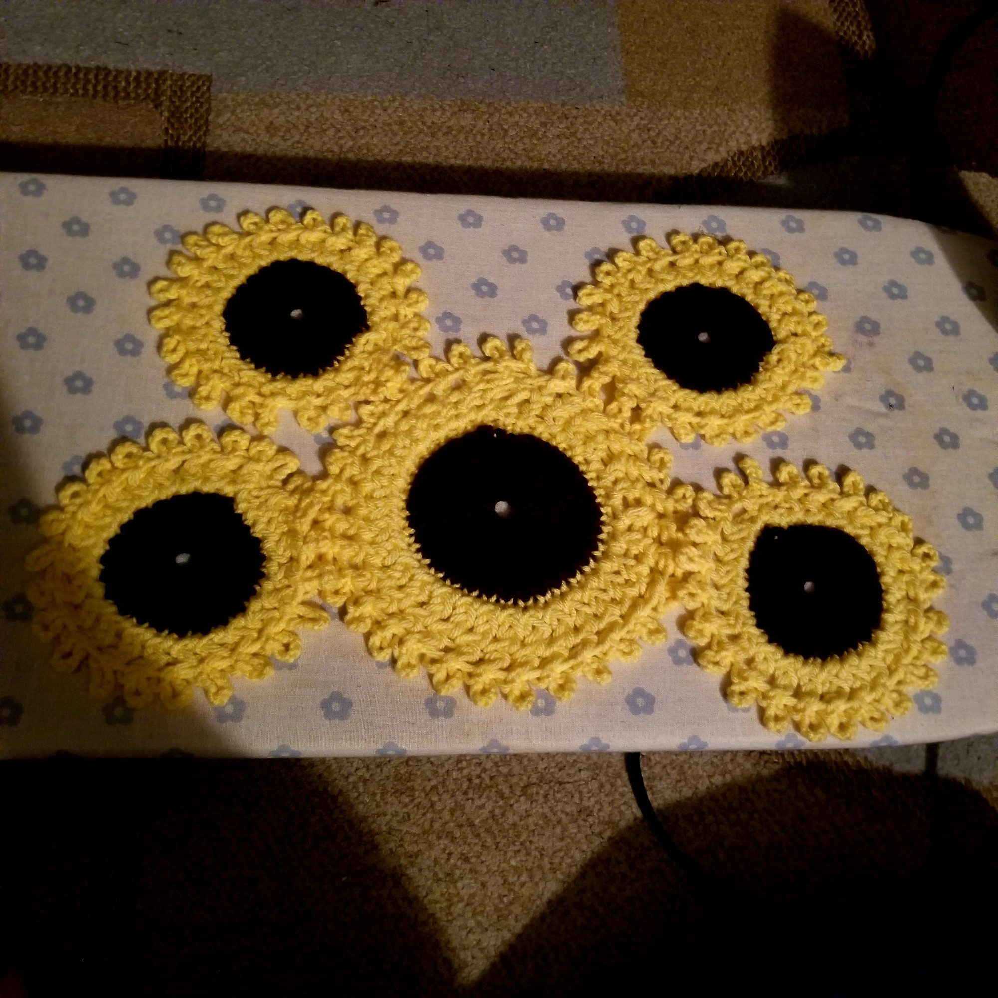 Lacy coasters shaped like sunflowers. There are four cup-sized ones, and one large one for a tea pot.