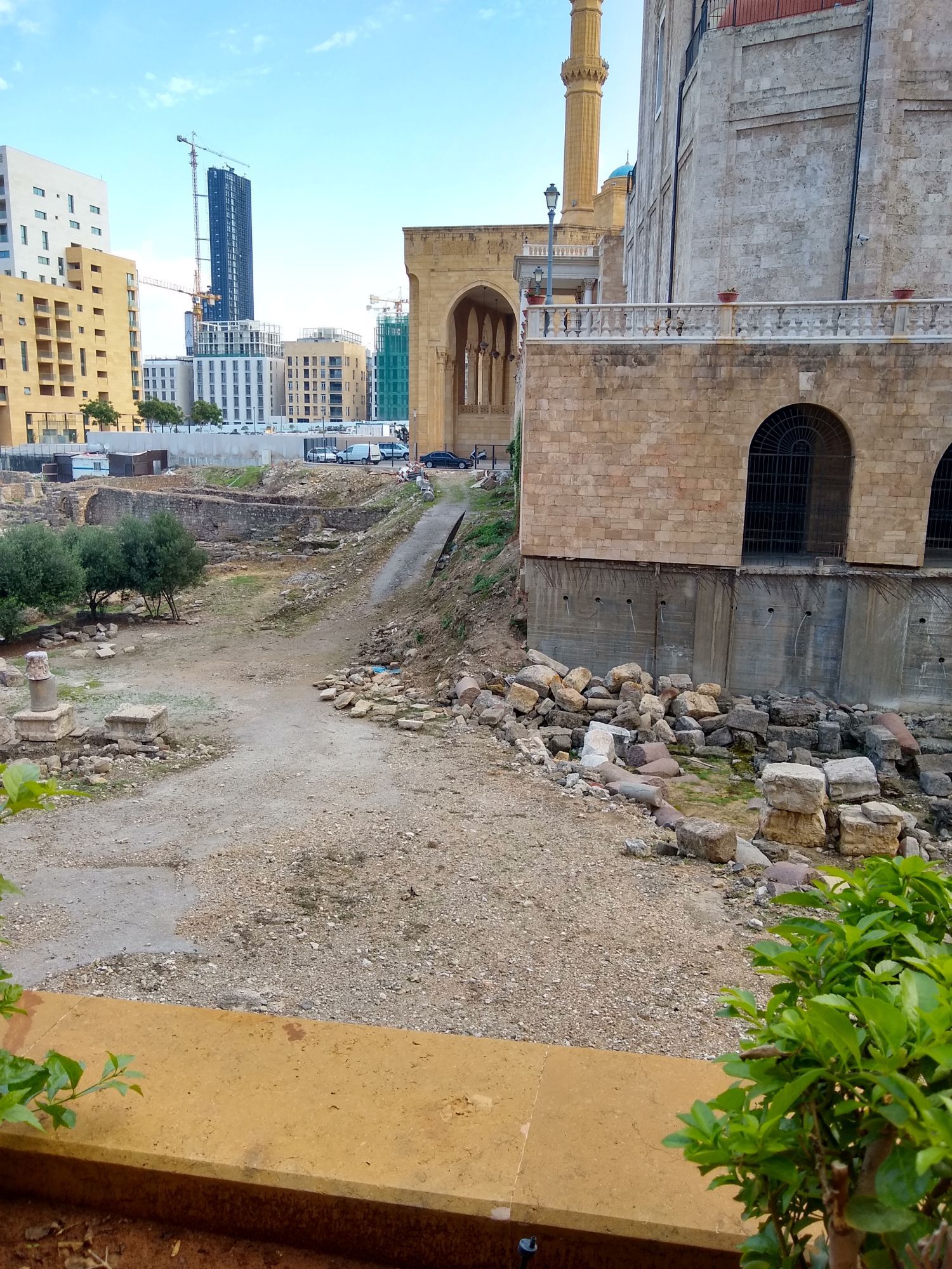 Roman Ruins in a protected area, the back of a mosque, and an office tower under construction.