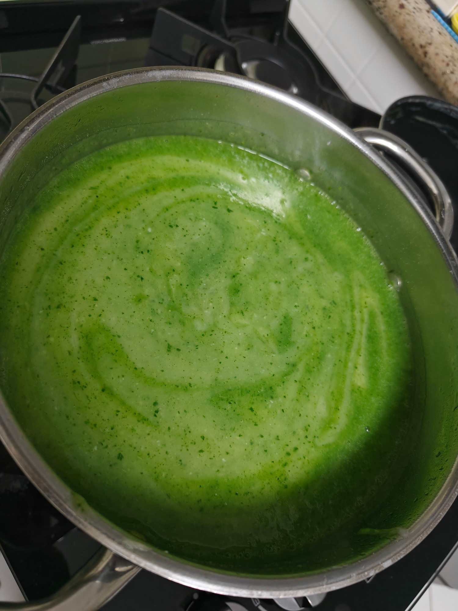 Panela de inox com um caldo verde em dois tons mesclados