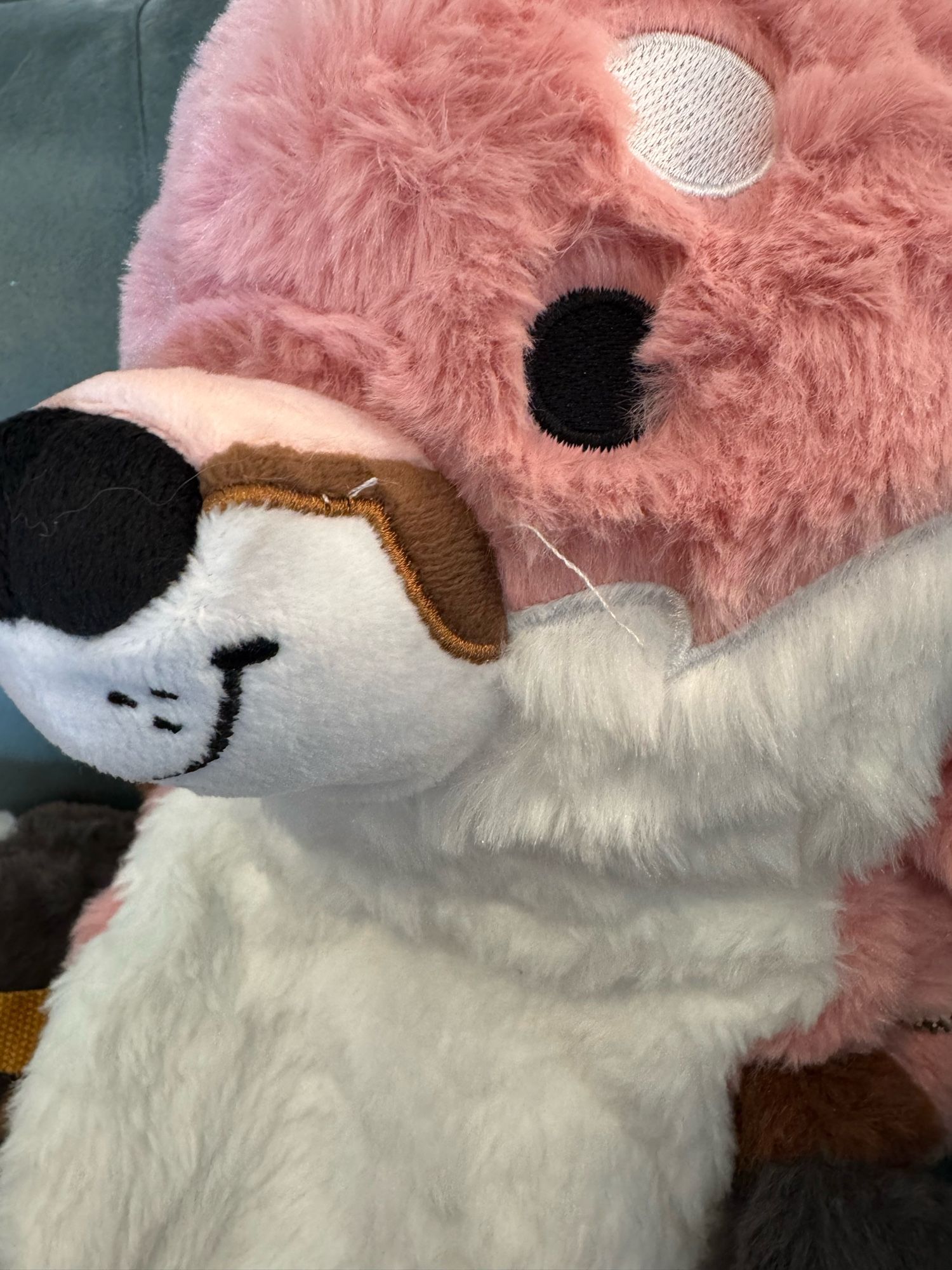 Close-up of the plush fox’s face with embroidered features showing a couple of loose white heads to trim. The fur along the seam where the pink fur meets the white also needs to be brushed out.