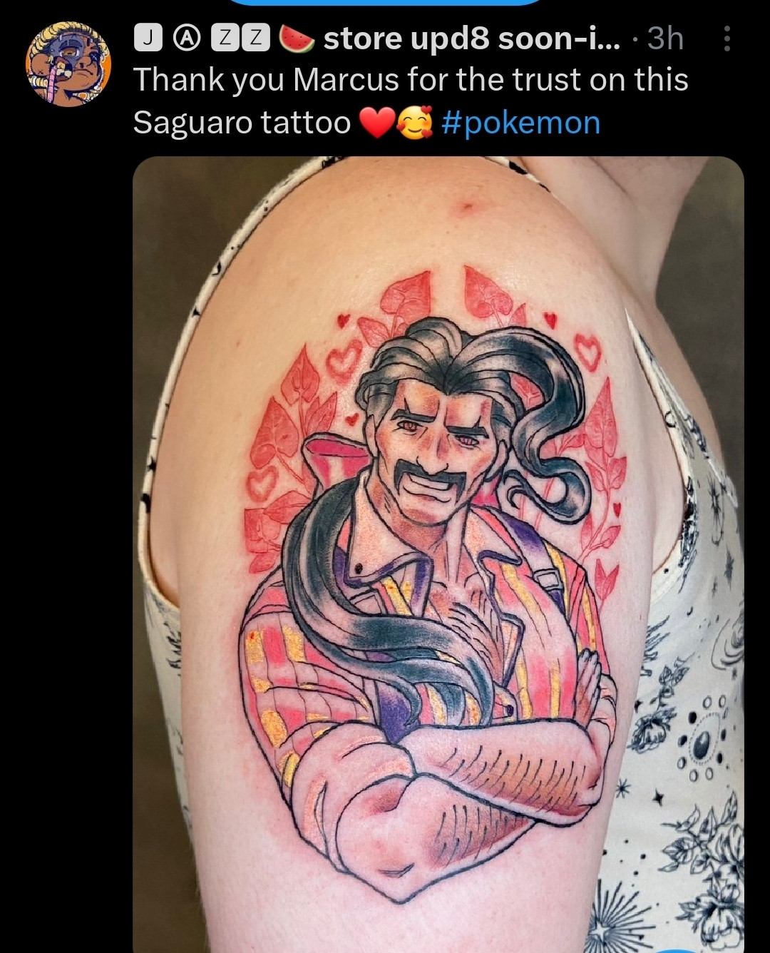 Shows side arm with a large tattoo of the character Instructor Saguaro the home economics teacher from Pokémon Scarlet and Violet. With his arms crossed smiling and sweet herba mystica behind him. 