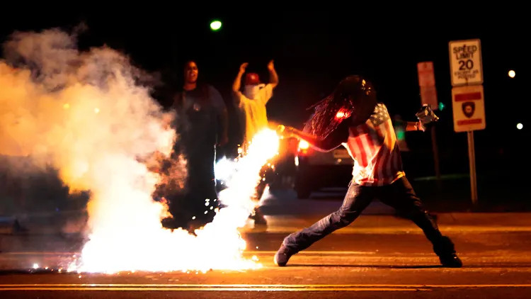 Edward Crawford throws back a tear gas container