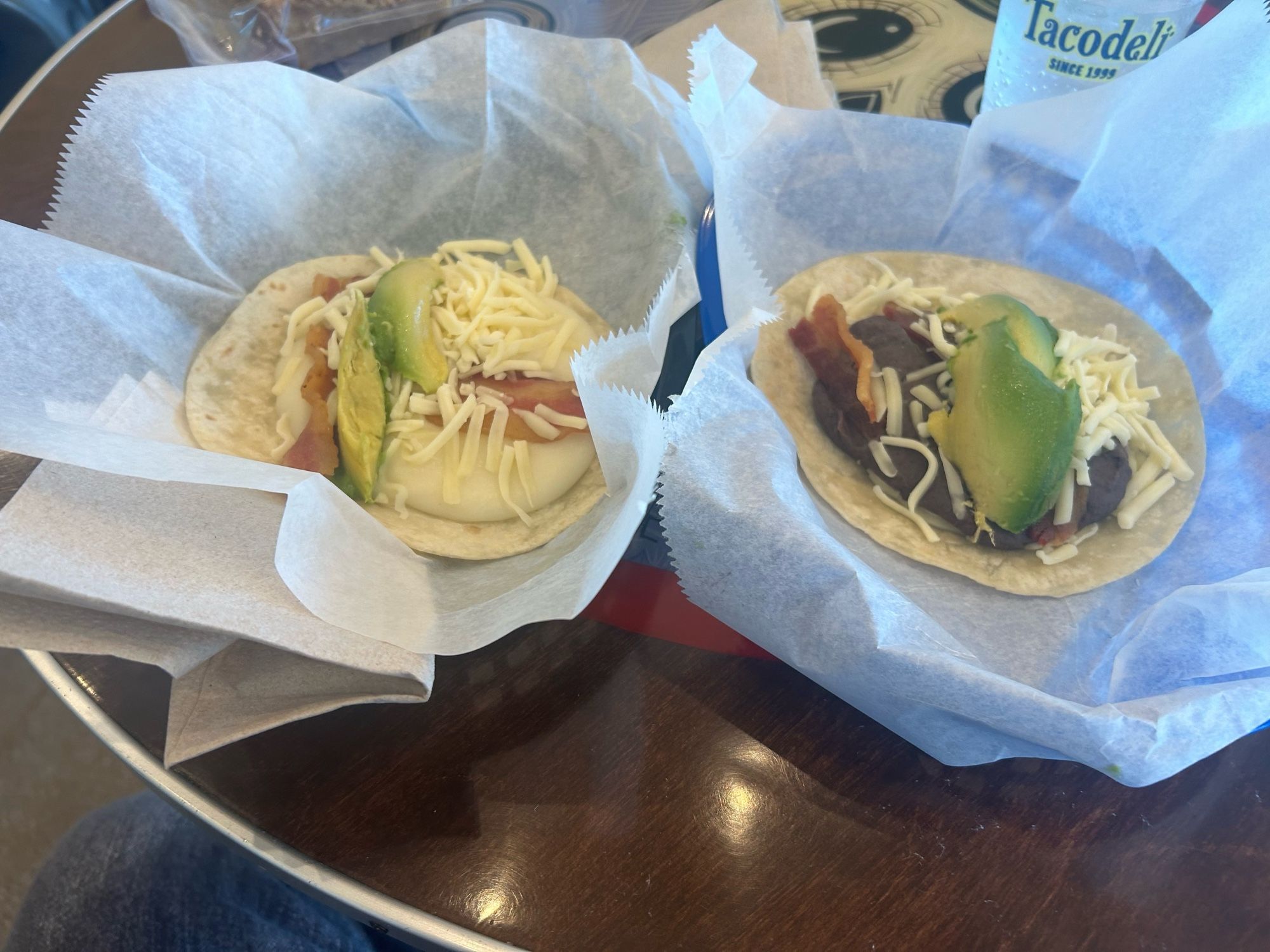 2 tacos, 1 in each basket. Right taco is an Otto, with beans, avocado, cheese, and bacon. On the left is a “DanL” which is the same as the Otto except that it has potatoes instead of beans.