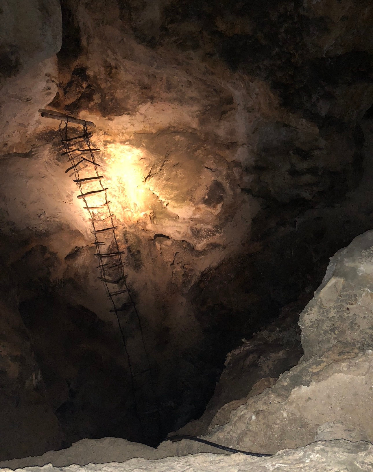 A old wooden ladder in a cave descending into darkness